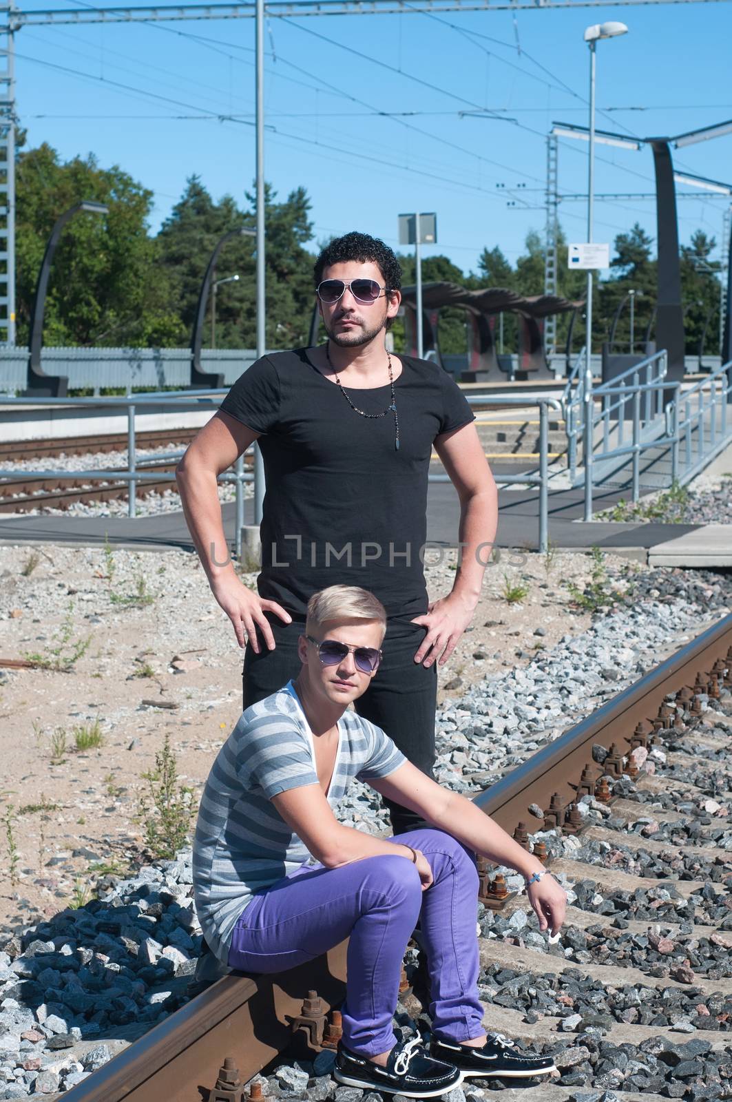 Shot of two guys on train tracks, focus on man in black