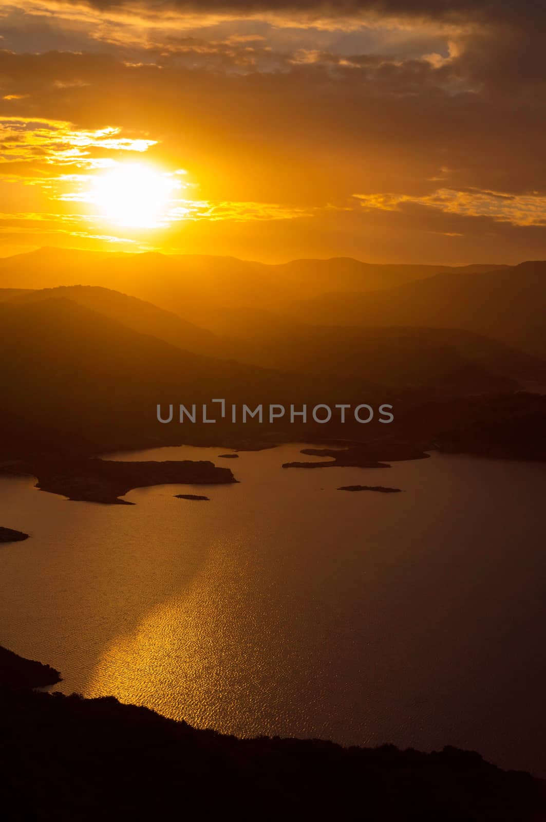 Landscape of sunset on the lake with the sun between the mountains