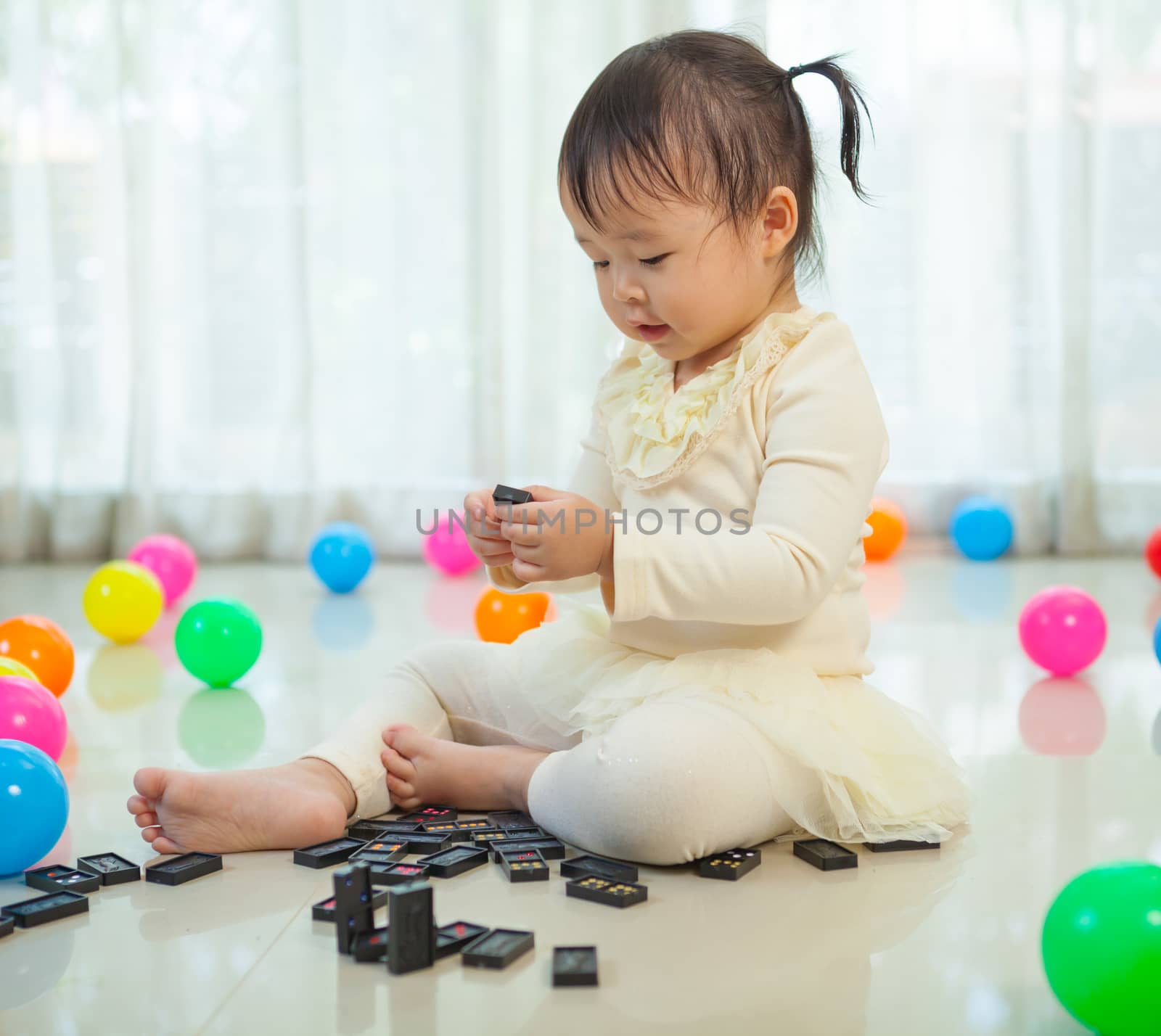 Cute little asian girl playing with black domino in the house