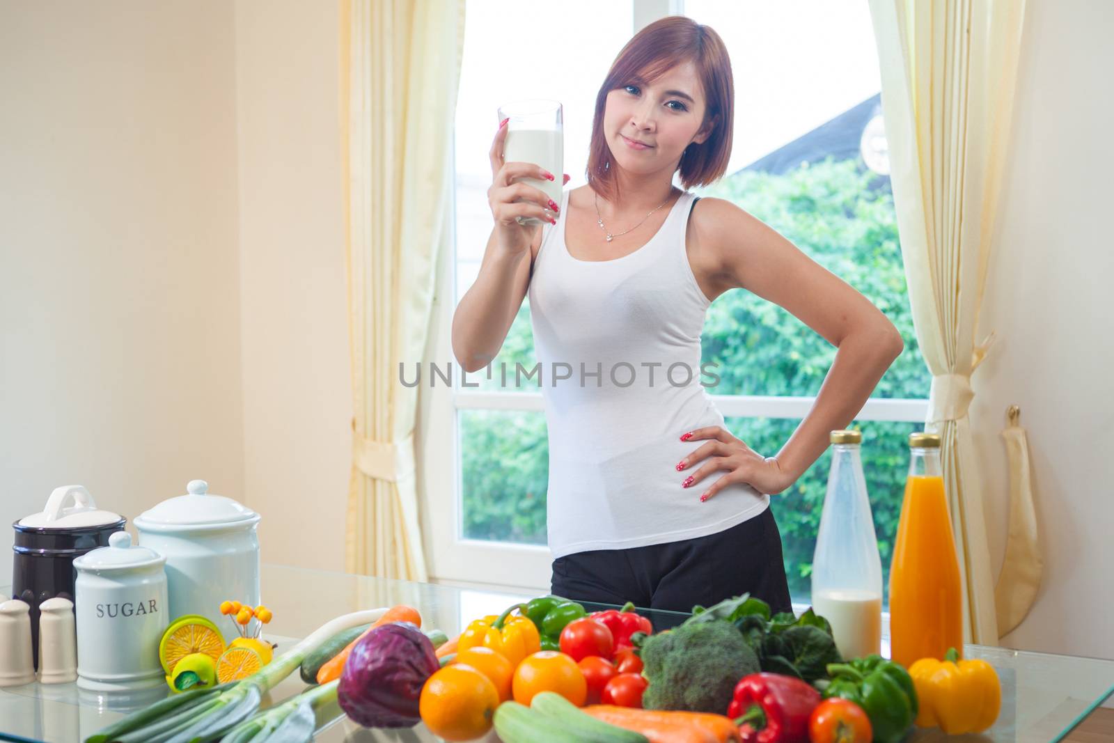 Young asian woman drinking milk in kitchen