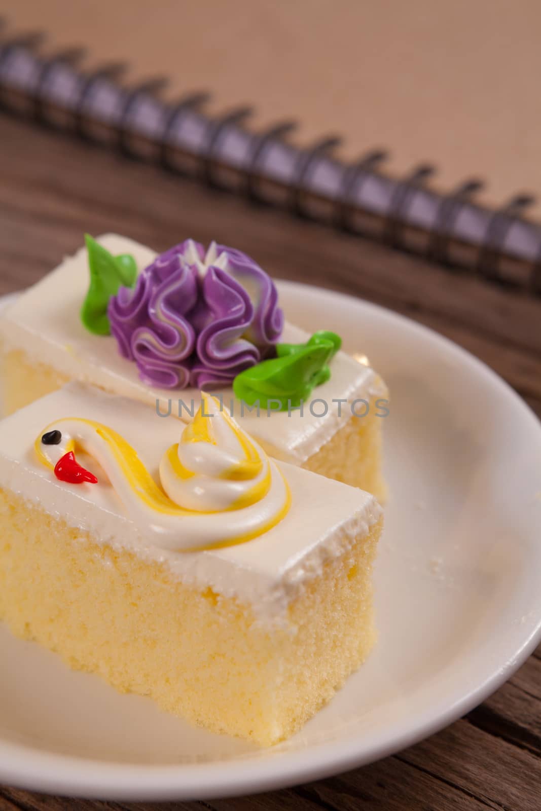 Flower Cake in white dish and notebook on the wood table