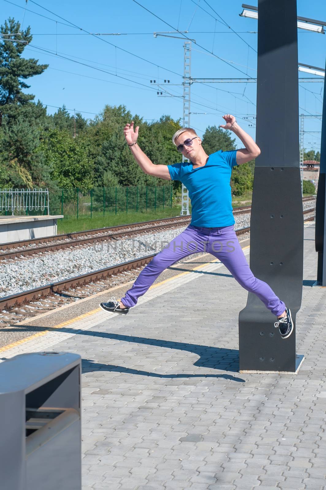 Handsome young guy jumping near rail track