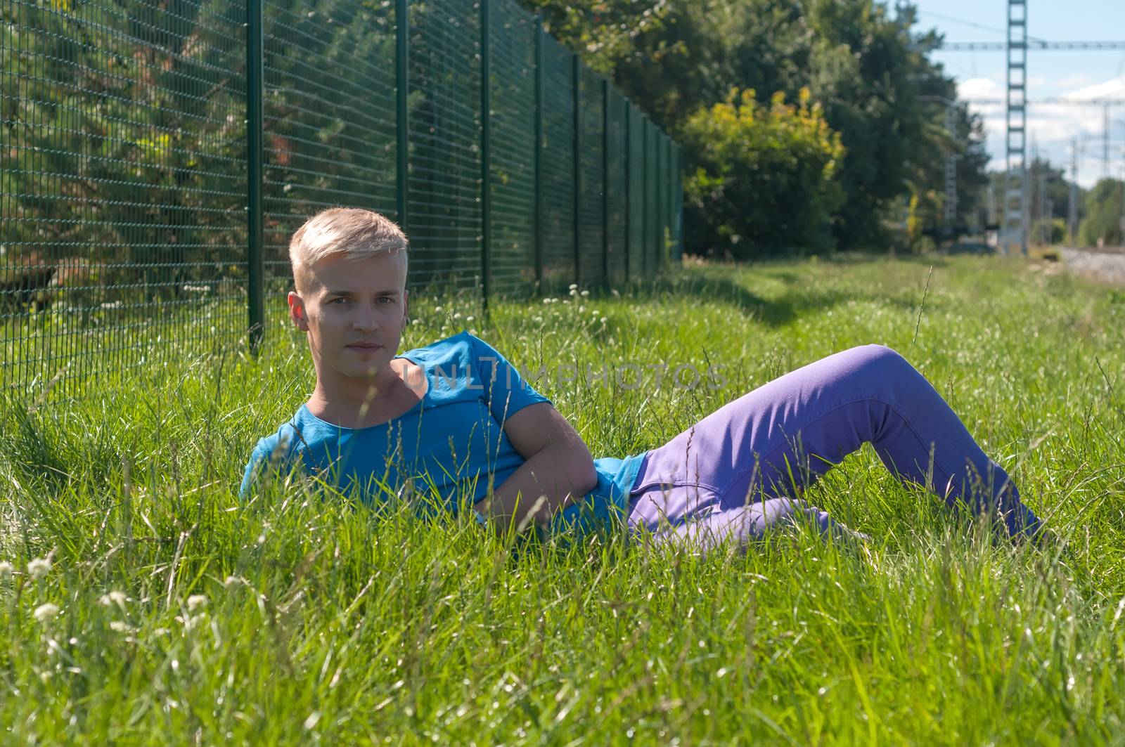 Young an in blue t-shirt lying on the grass
