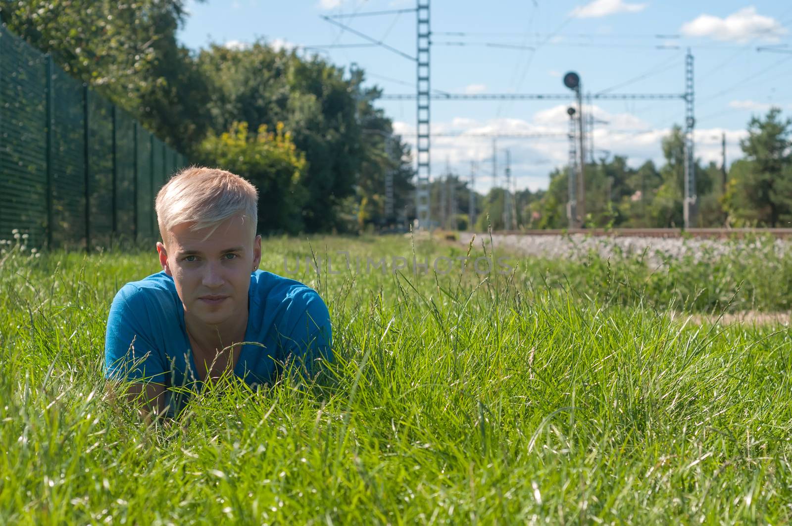 Young man in blue lying on the green grass by anytka