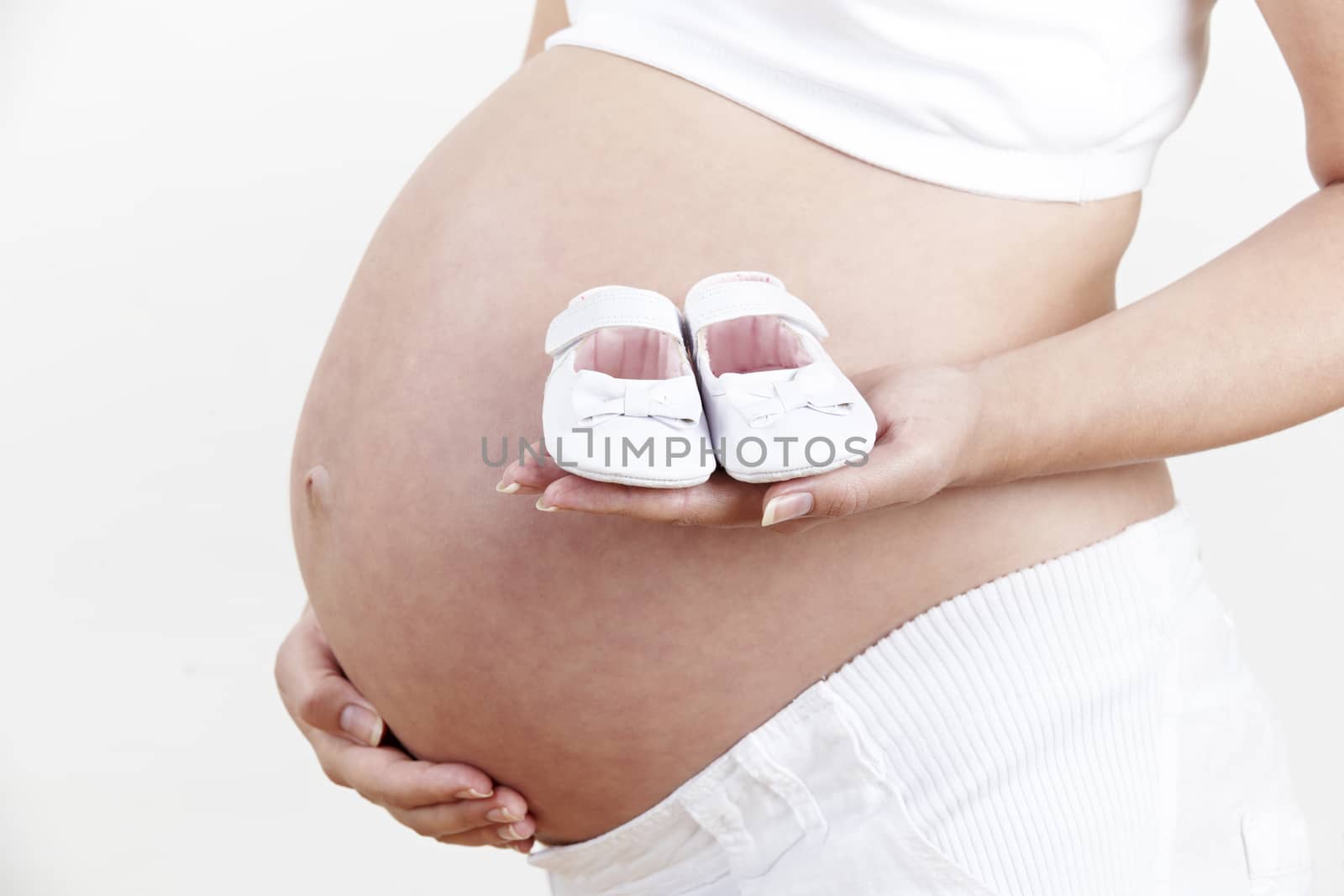 Close Up Of Pregnant Woman Holding Baby Shoes by HighwayStarz