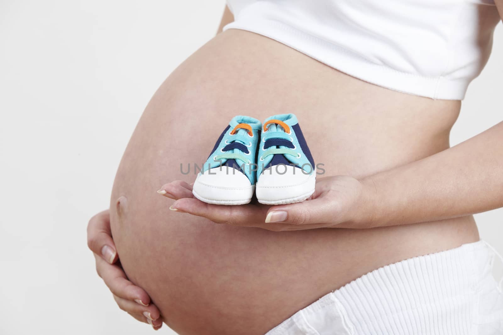 Close Up Of Pregnant Woman Holding Baby Shoes