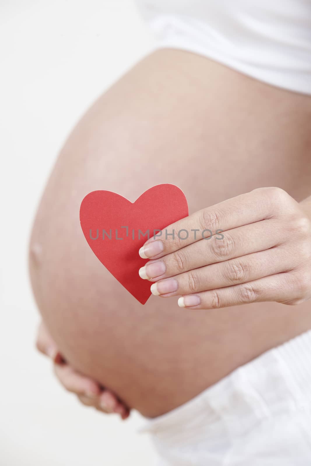 Close Up Of Pregnant Woman Holding Heart Shape by HighwayStarz