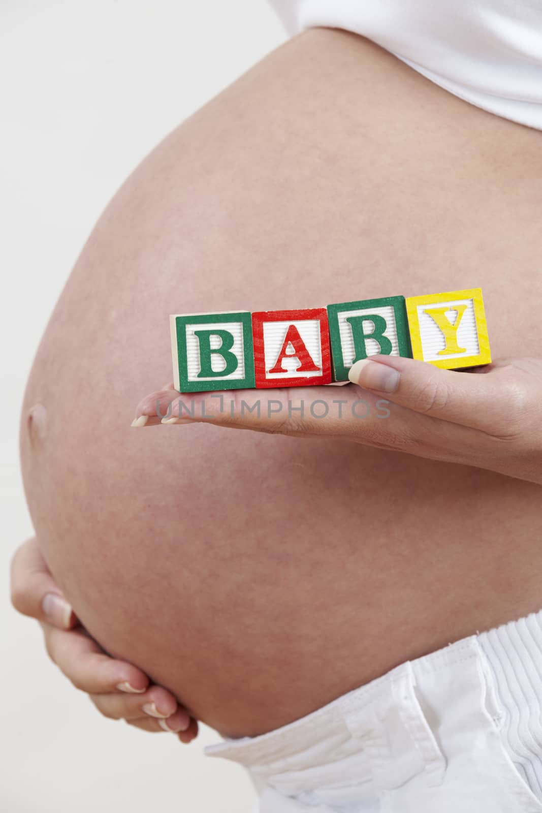 Close Up Of Pregnant Woman Holding Blocks Spelling Baby