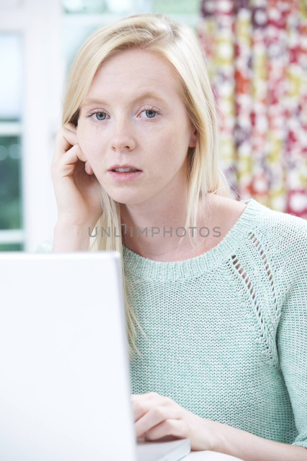 Worried Teenage Girl Using Laptop At Home