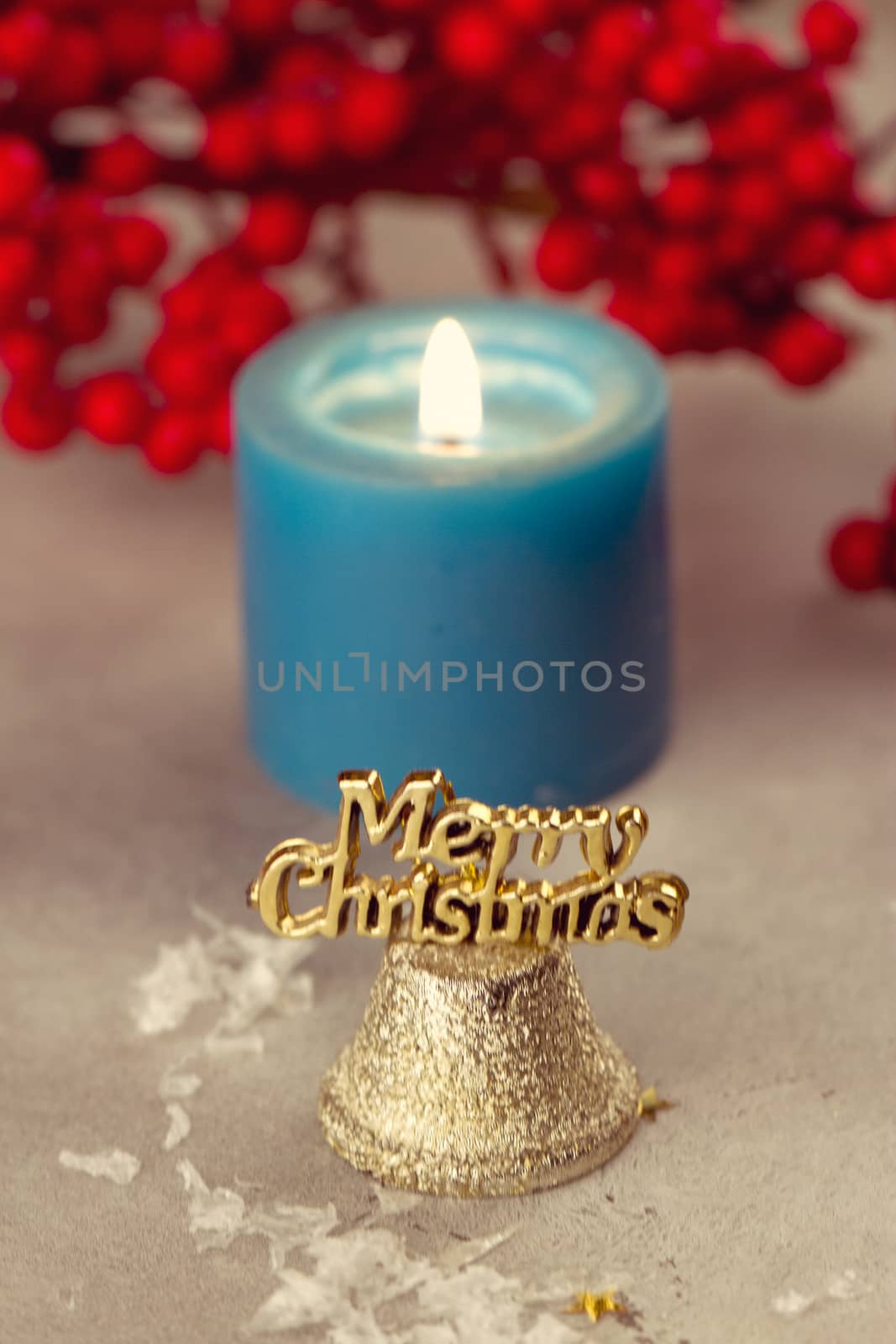Christmas bells near burning candles on a snowy background