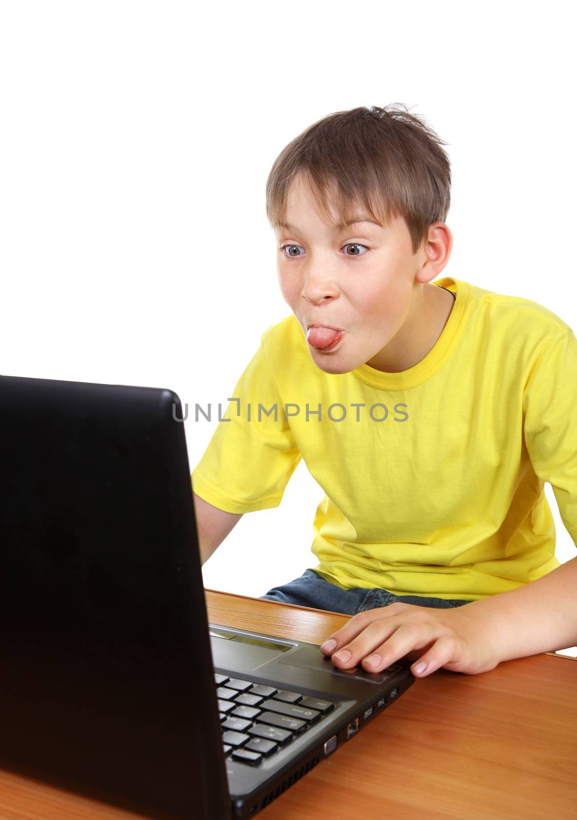 Kid at the Desk with Laptop showing a Tongue in Display on the White Background