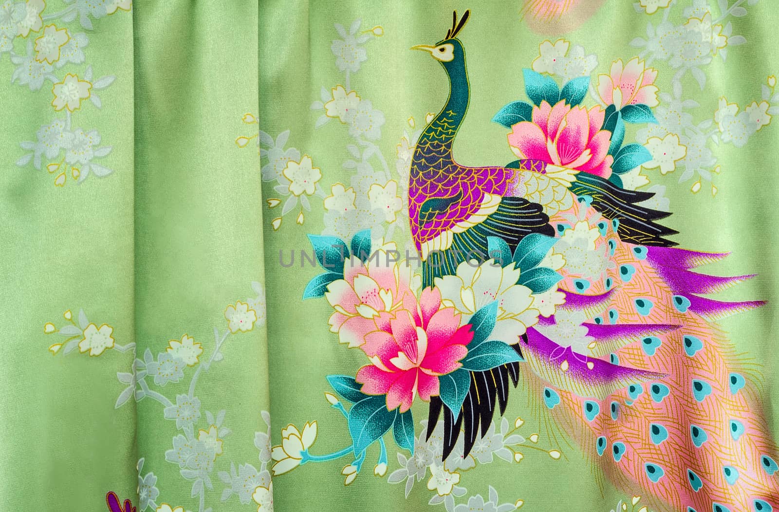 Beautiful silk fabric of light green color with the bright image of a peacock among flowers.g
