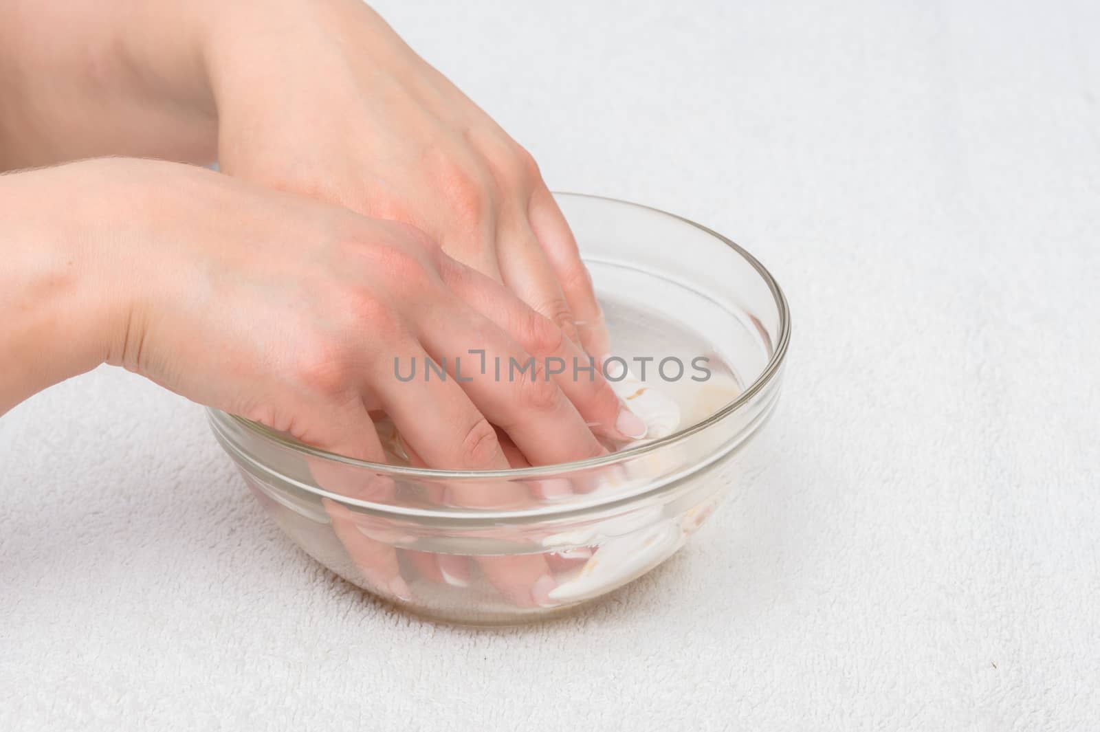 Hands moisturizing and mineralizing in water with seashells