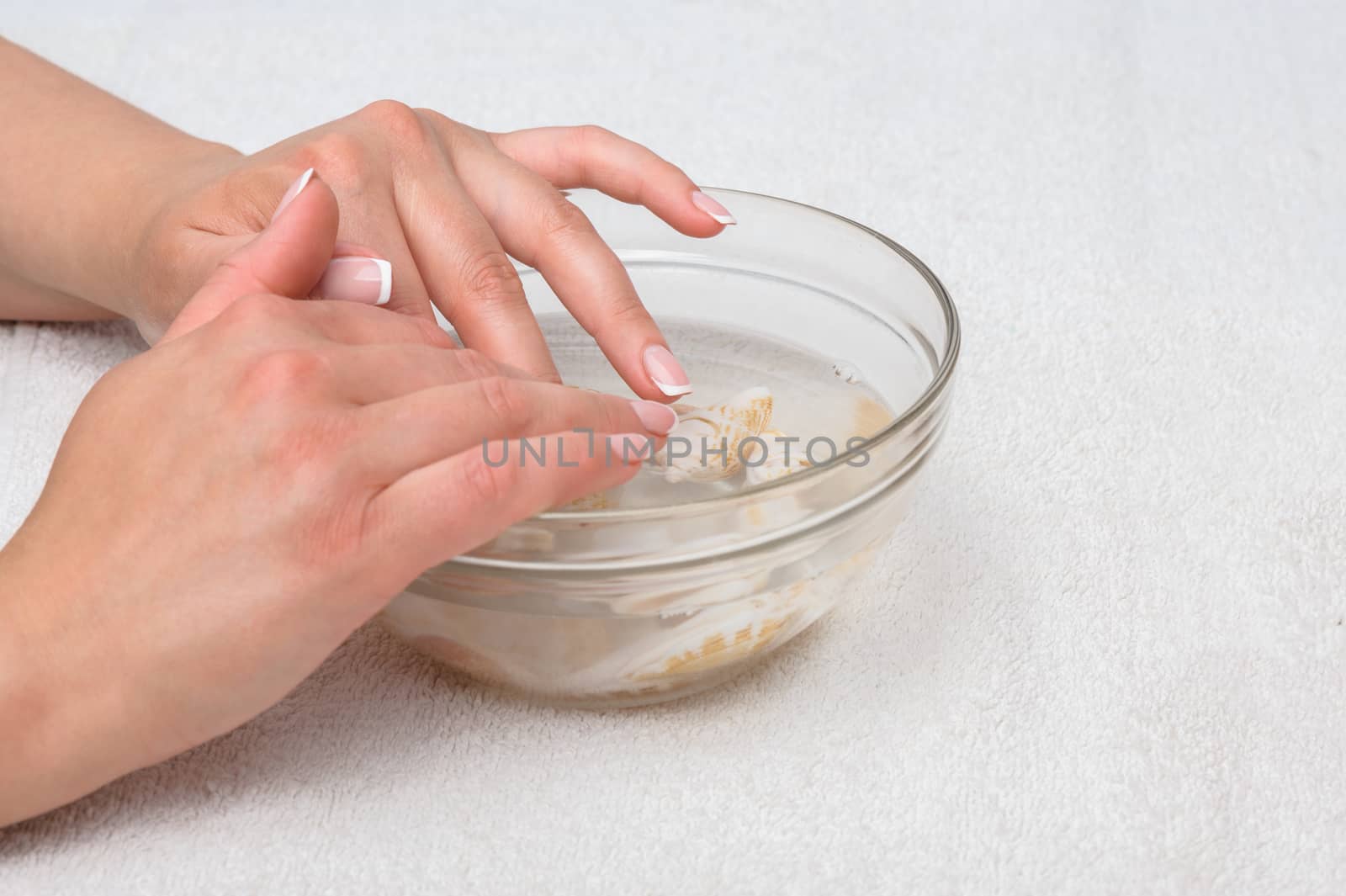 Hands moisturizing and mineralizing in water with seashells