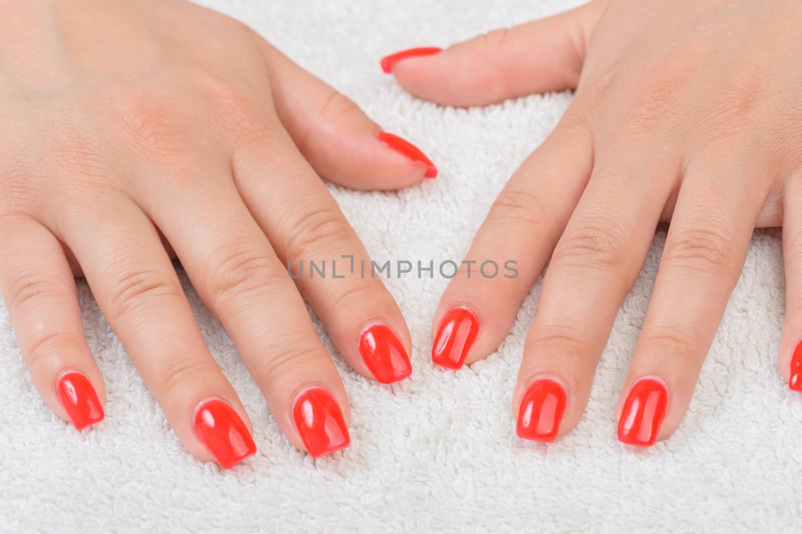 Female fingers with red enamel on white towel