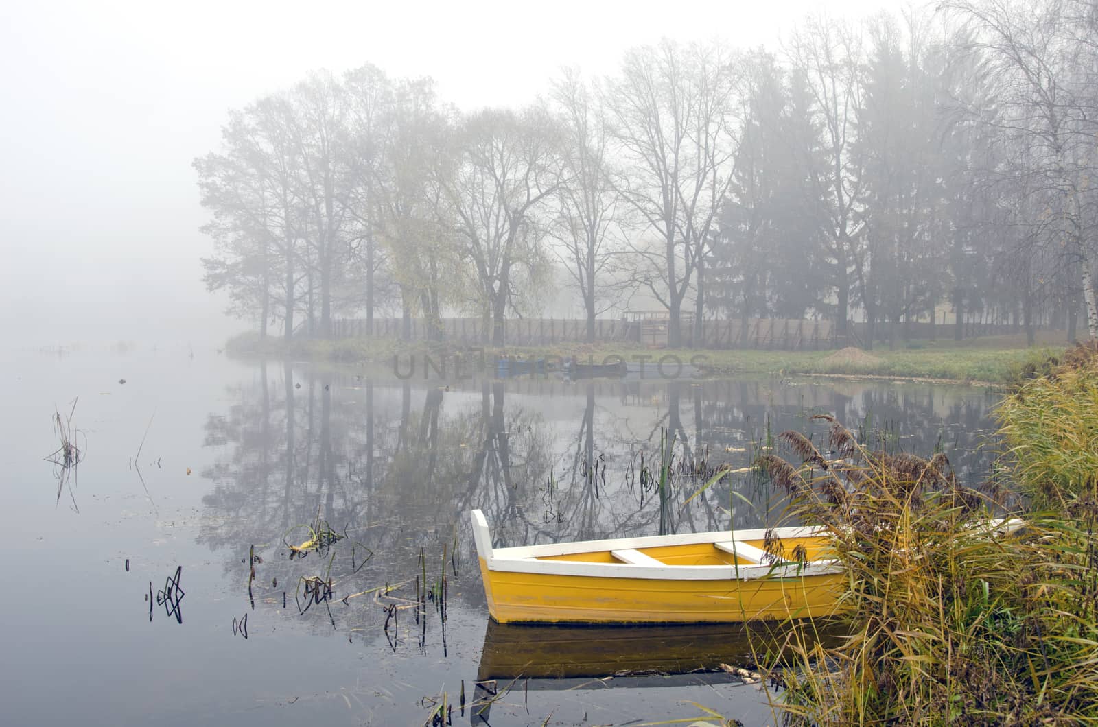 yellow wooden boat on autumn lake and early morning mist