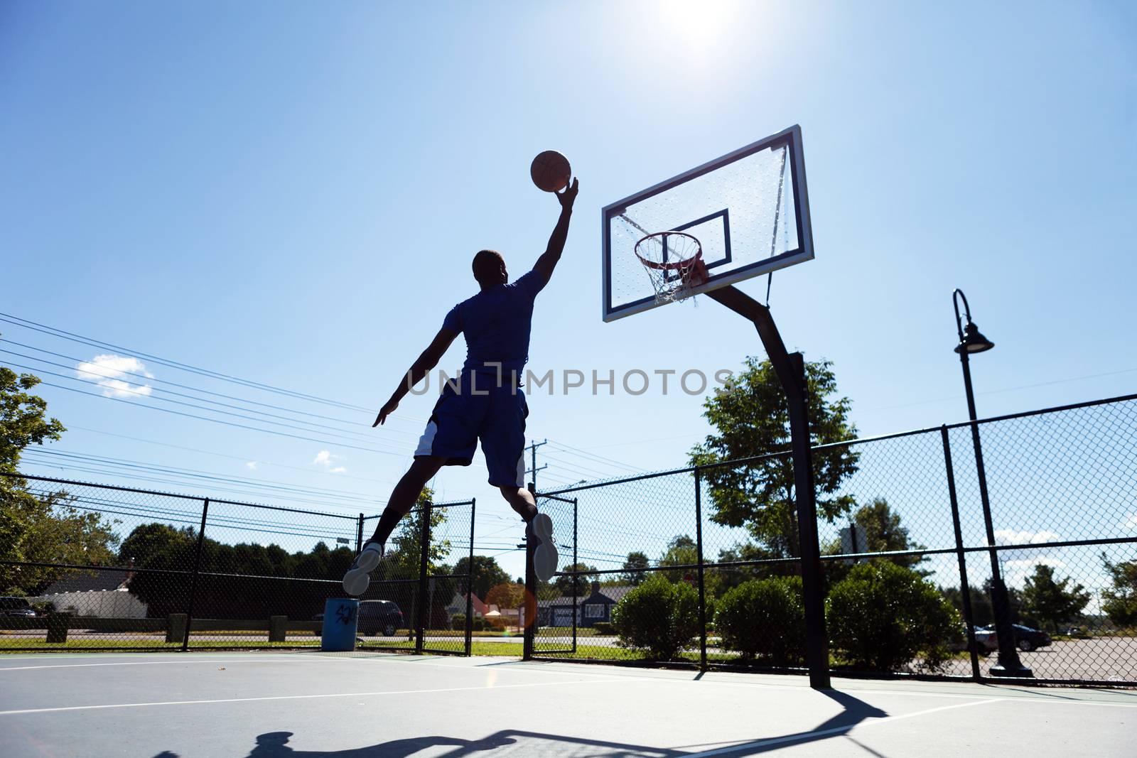 A young basketball player going up for a layup.  Intentionally back lit with bright lens flare.