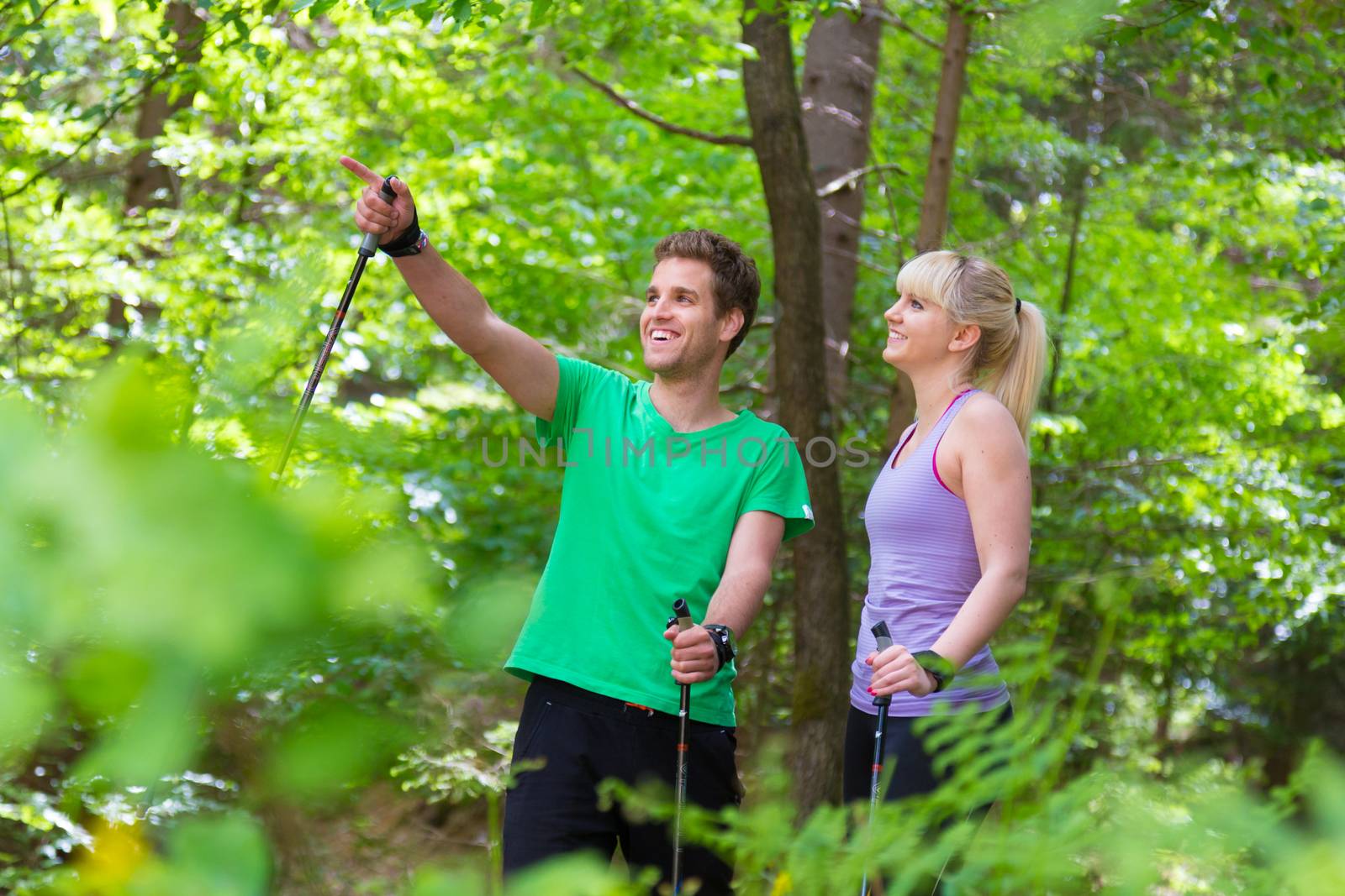 Young spoty active cople with hiking sticks walking in nature. Active lifestyle. Activities and recreation outdoors.