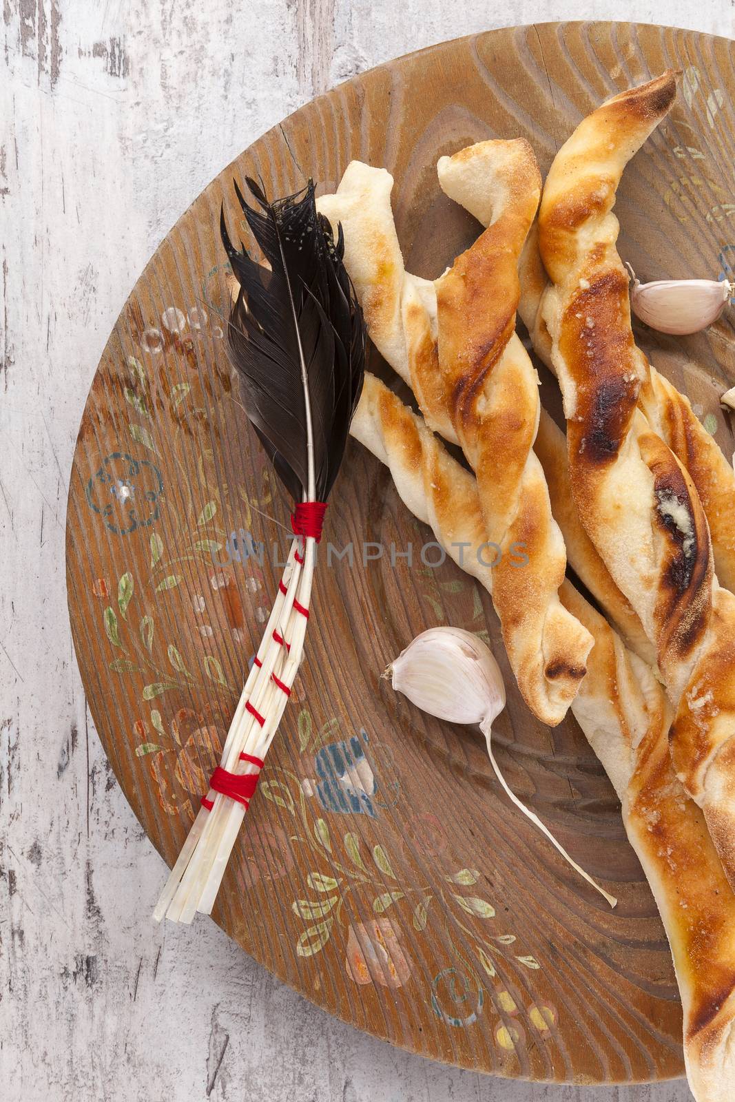 Pizza breadsticks on wooden plate on white wooden background. Culinary italian pizza eating. 