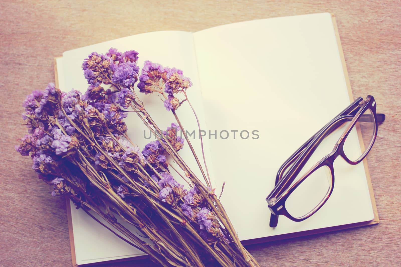 Blank notebook and dried statice flowers with eyeglasses, retro filter effect