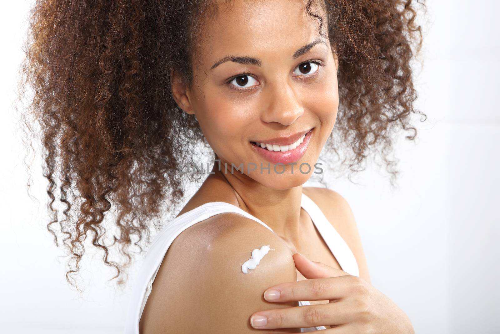 Care, dark skinned teen smiles rubbing cream by robert_przybysz