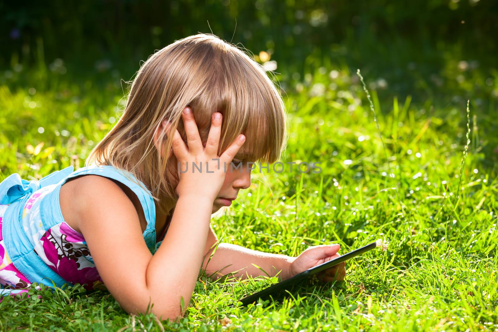 Child with a tablet computer outdoor by naumoid