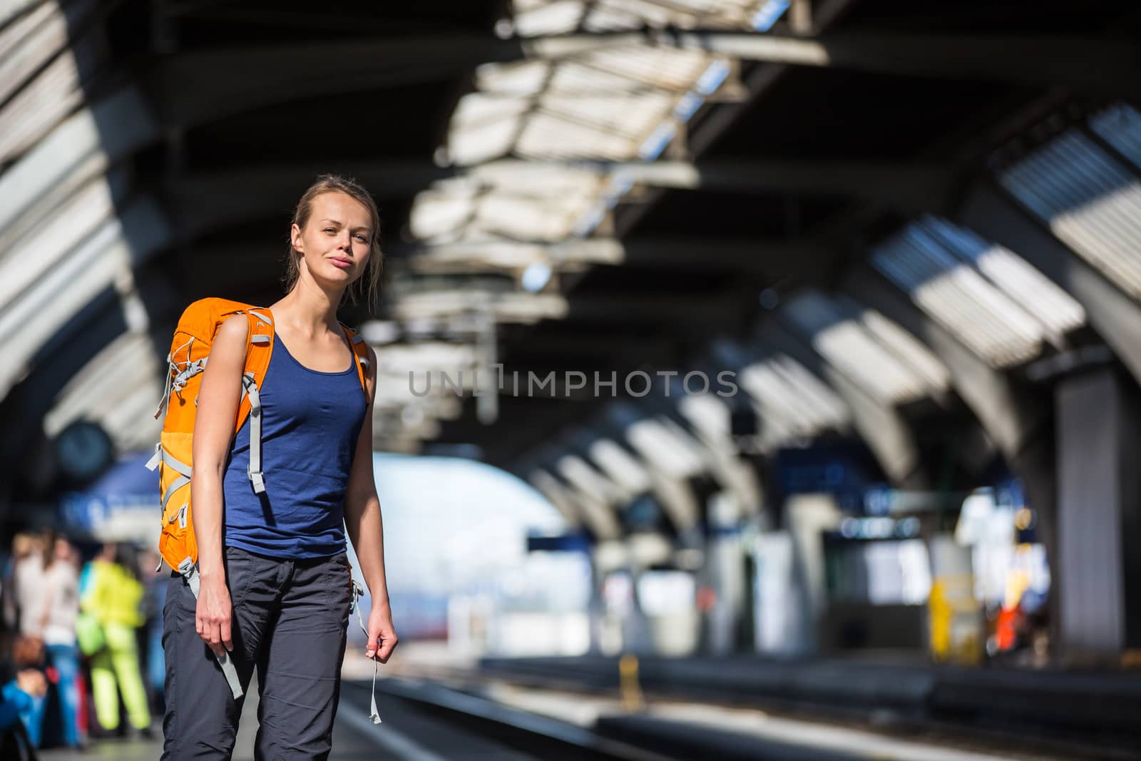 Pretty, young woman in a trainstation, waiting for her train, boarding a train (color toned image)