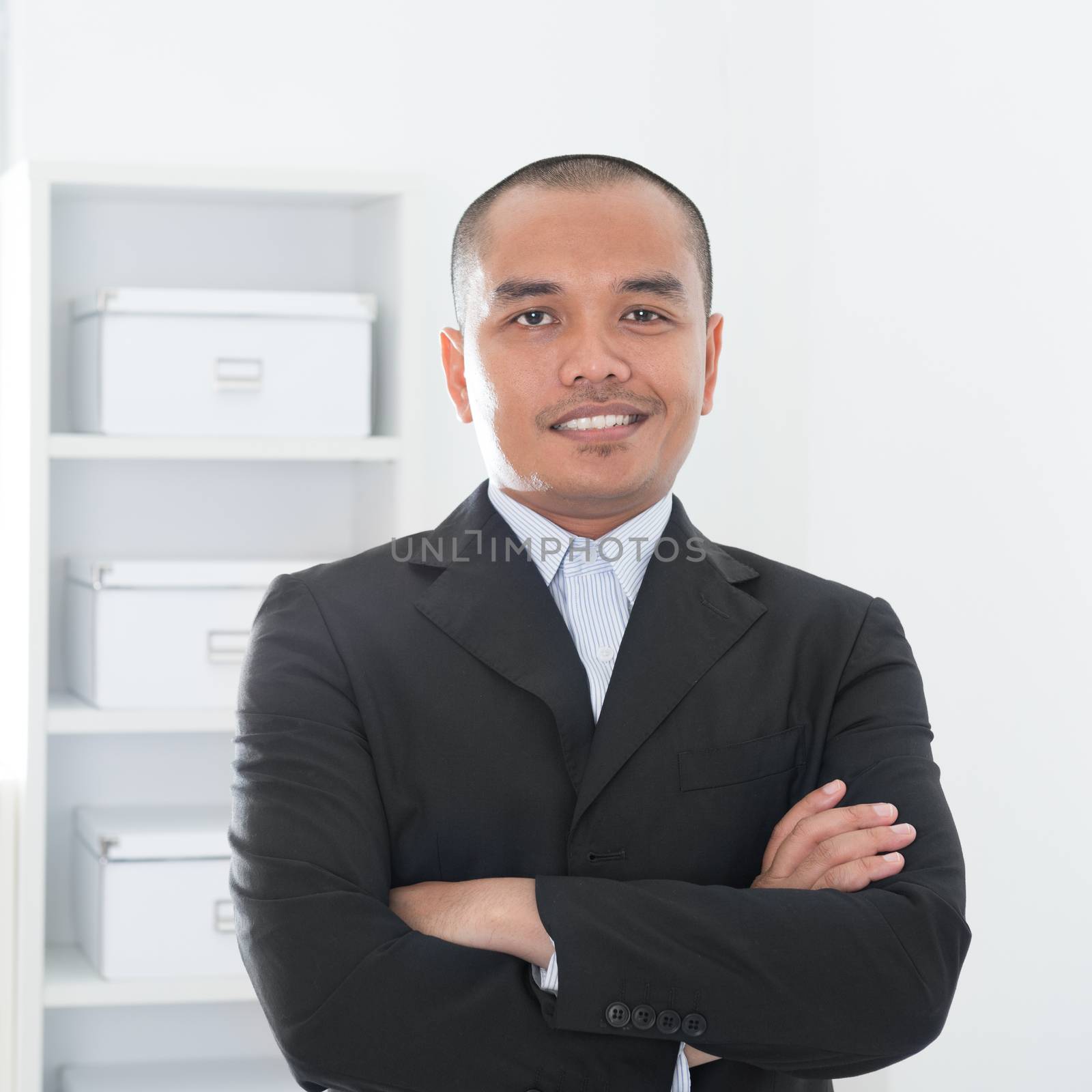 Portrait of 30s Asian Muslim business man smiling, real modern office background.