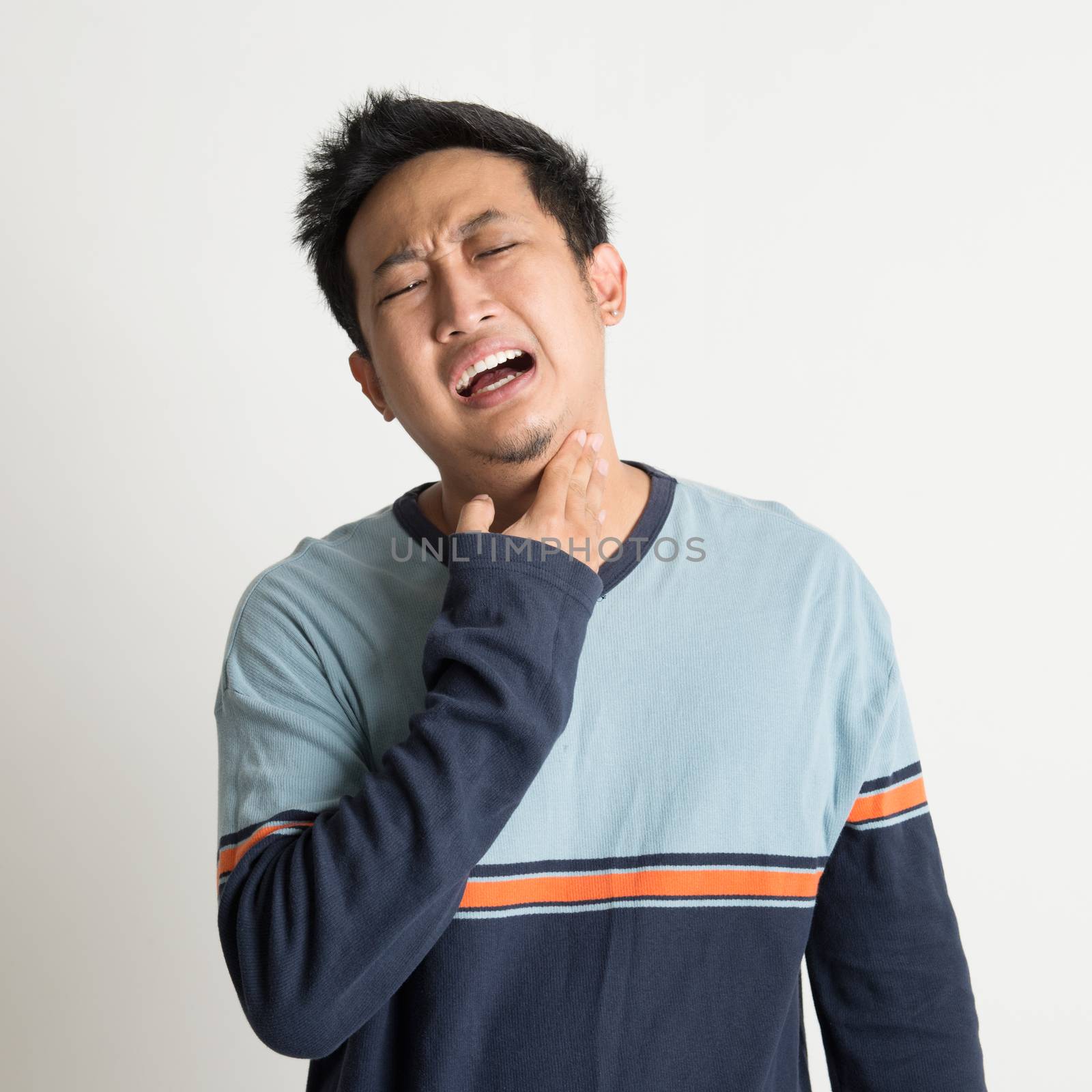 Asian male sore throat with painful face expression, on plain background