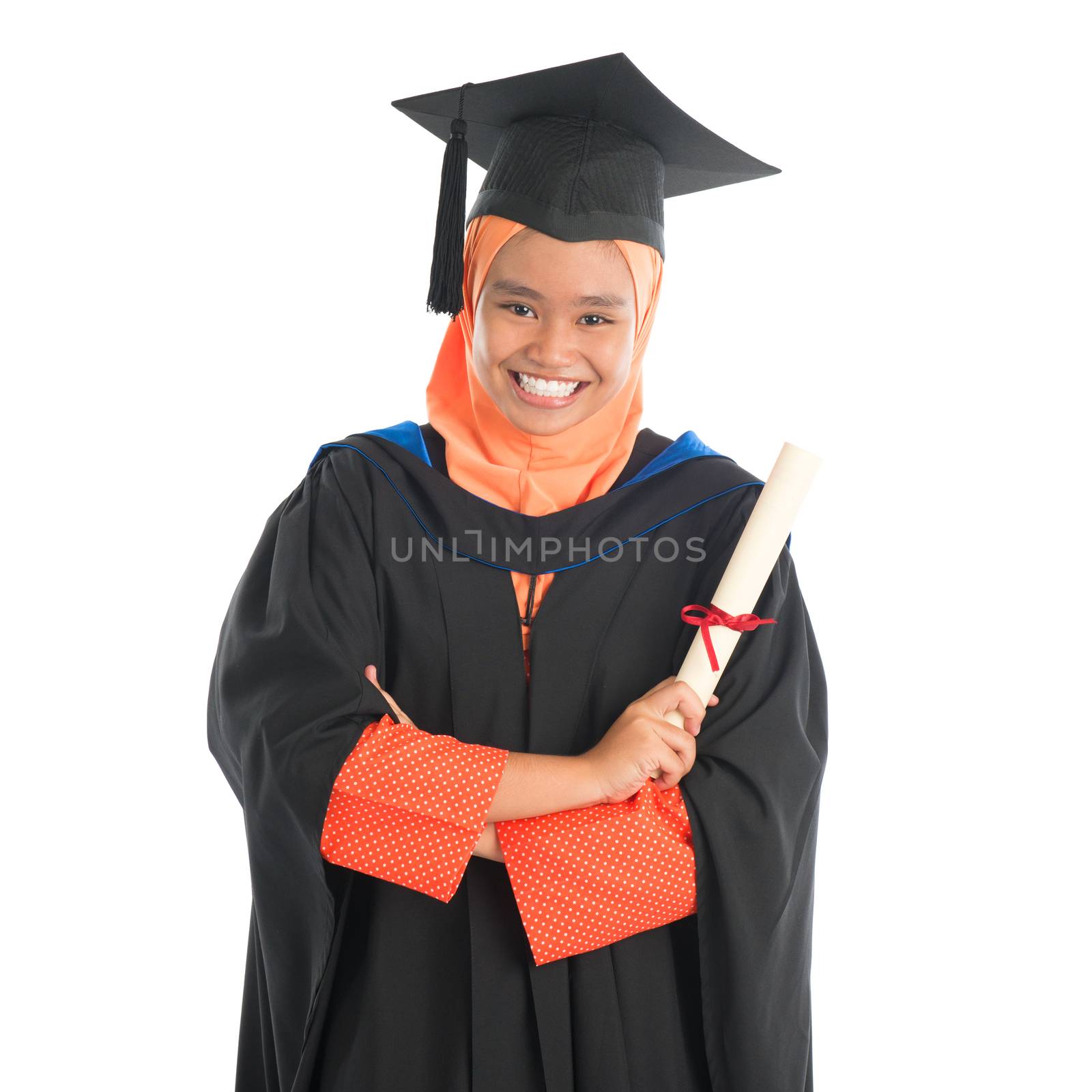 Portrait of smiling Asian female Muslim student in graduate gown showing graduation diploma standing isolated on white background.