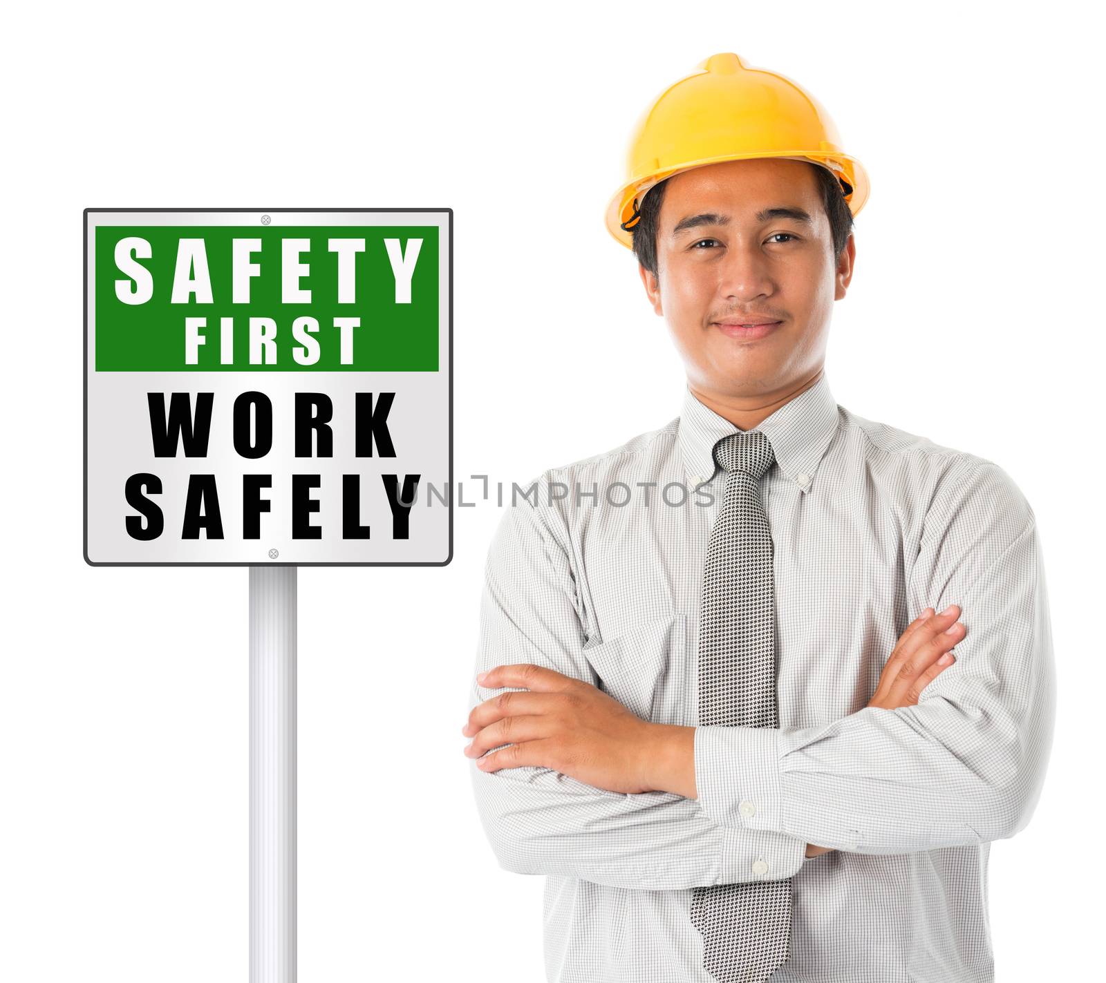 Asian male worker wearing a hardhat smiling and looking at camera, arms crossed standing beside safety first sign board, isolated on white background.