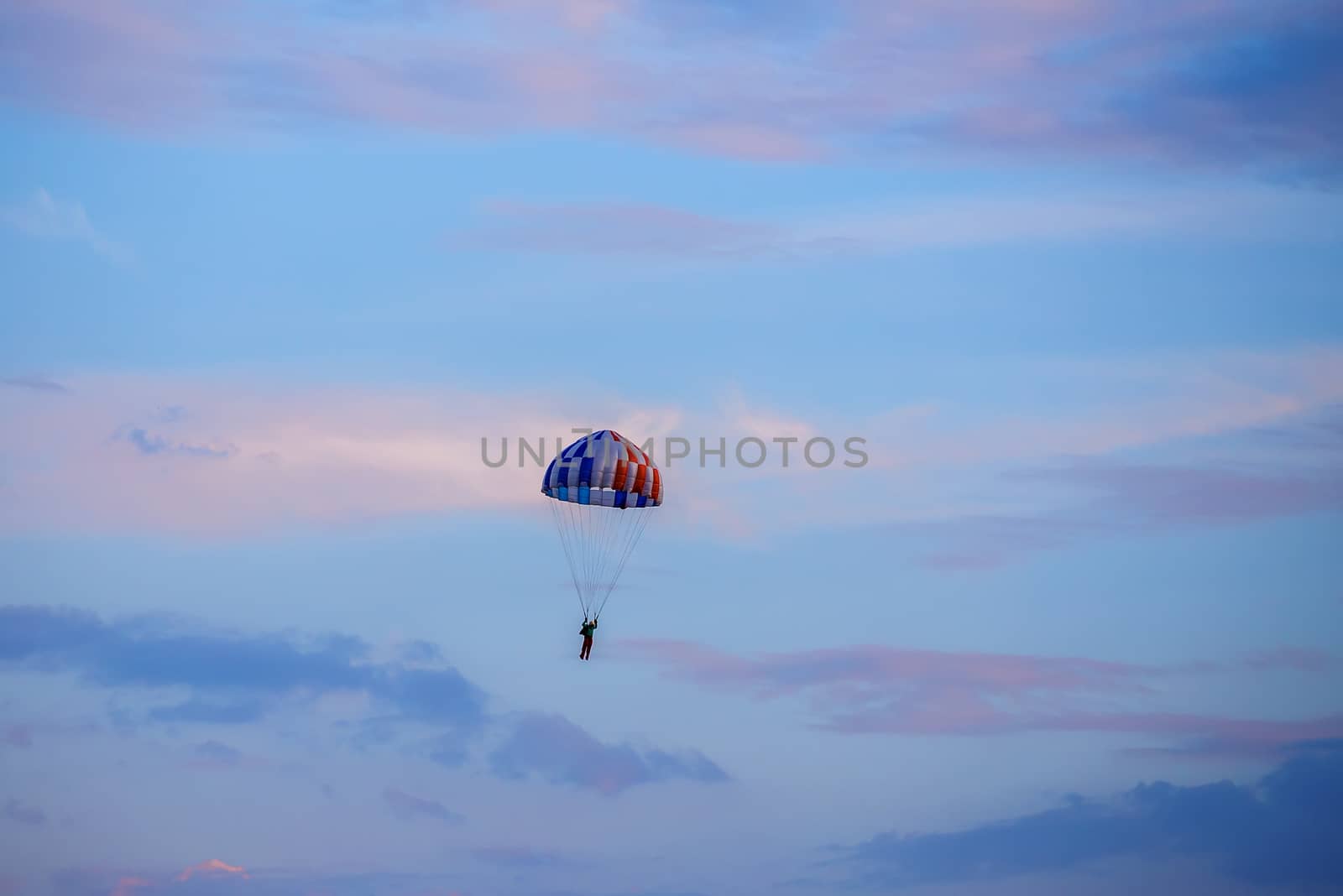 silhouette of unidentified skydiver parachutist on blue sky on sunset