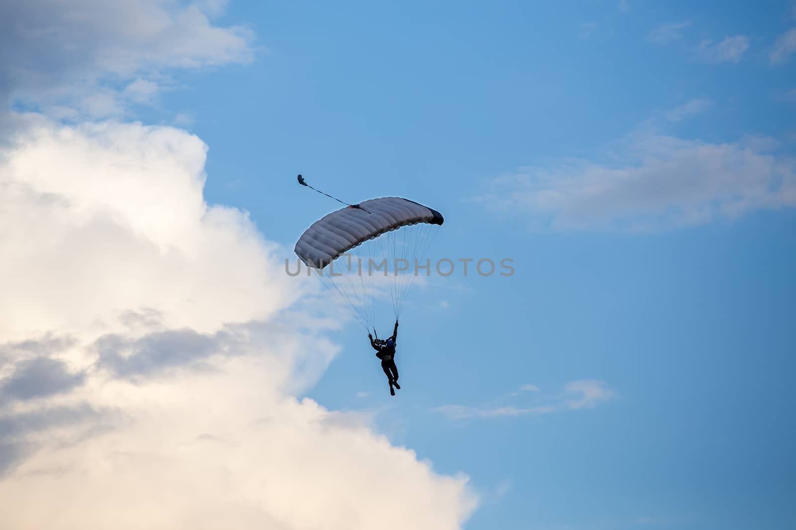 silhouette of unidentified skydiver parachutist on blue sky on sunset