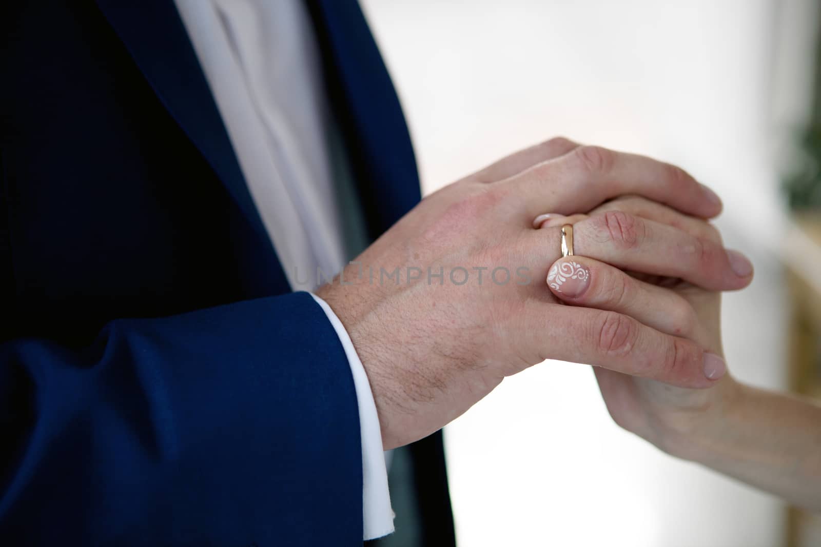 hands of a bride and a groom, woman putting a wedding ring on the finger of her groom