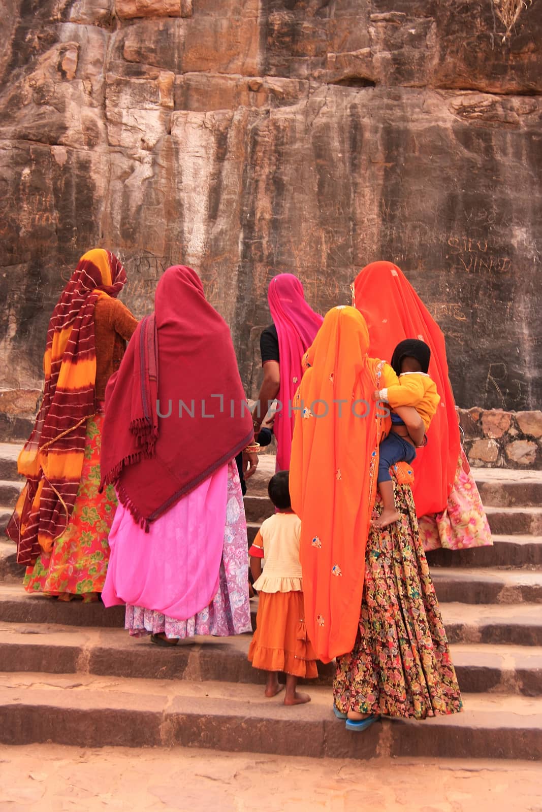 Indian women in colorful saris with kids walking up the stairs a by donya_nedomam