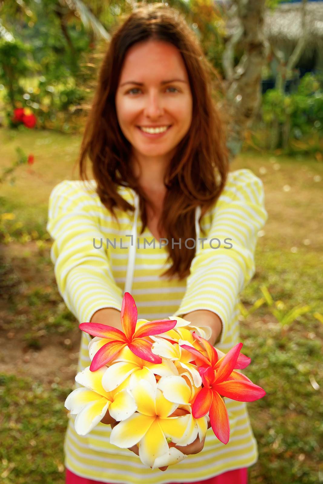 Young woman holding white and pink plumeria flowers in her hands by donya_nedomam