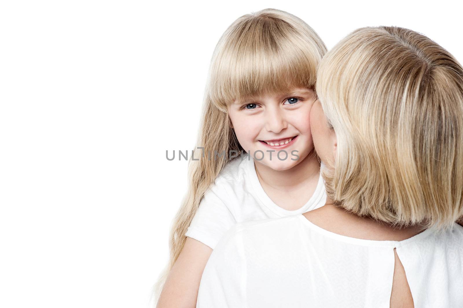 Mother kissing her daughter while daughter posing to the camera