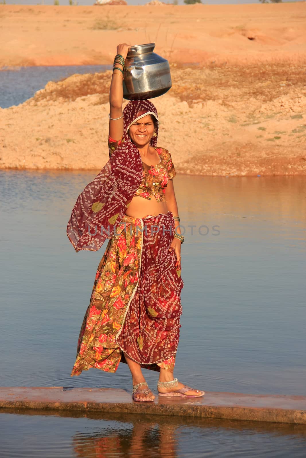 Local woman carrying jar with water on her head, Khichan village by donya_nedomam