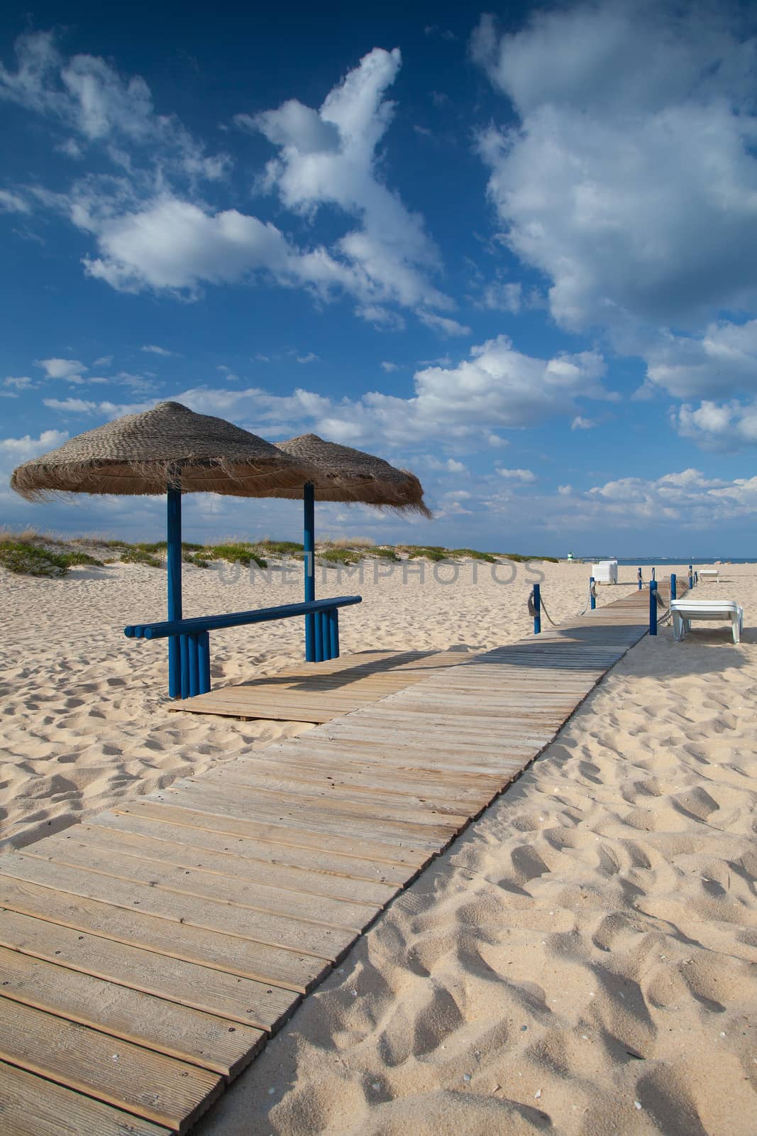 Different parasols and sun loungers on the empty beach on Tavira by CaptureLight