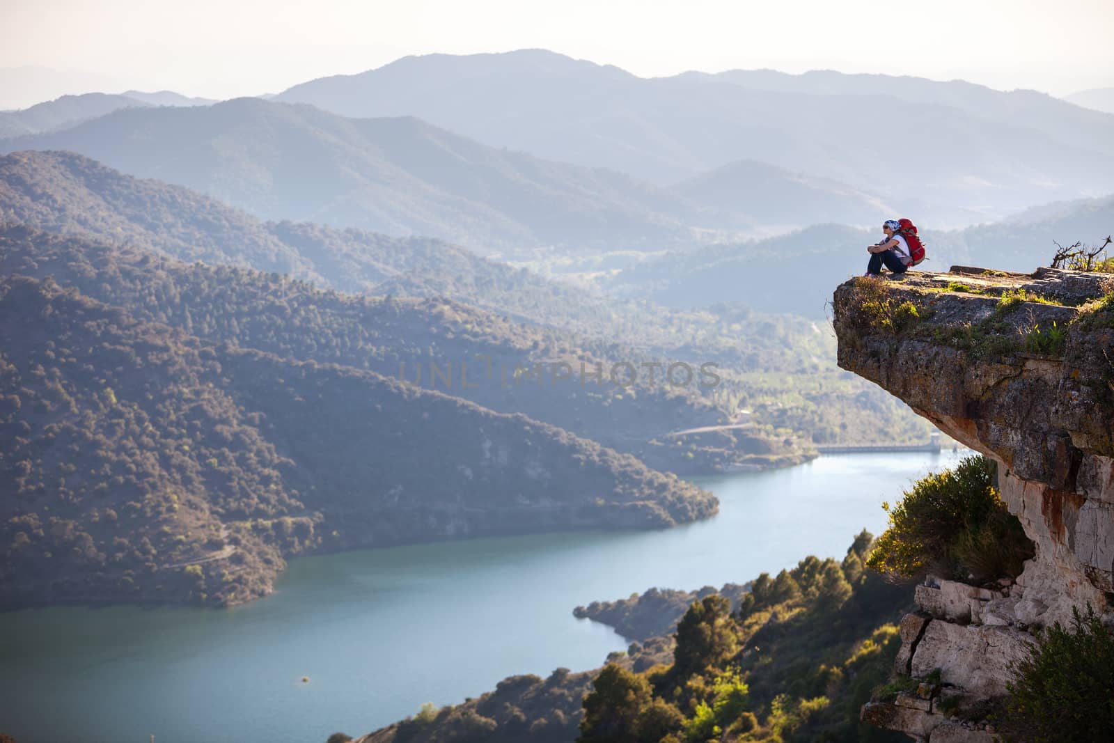Female hiker sitting on cliff and enjoying view by photobac