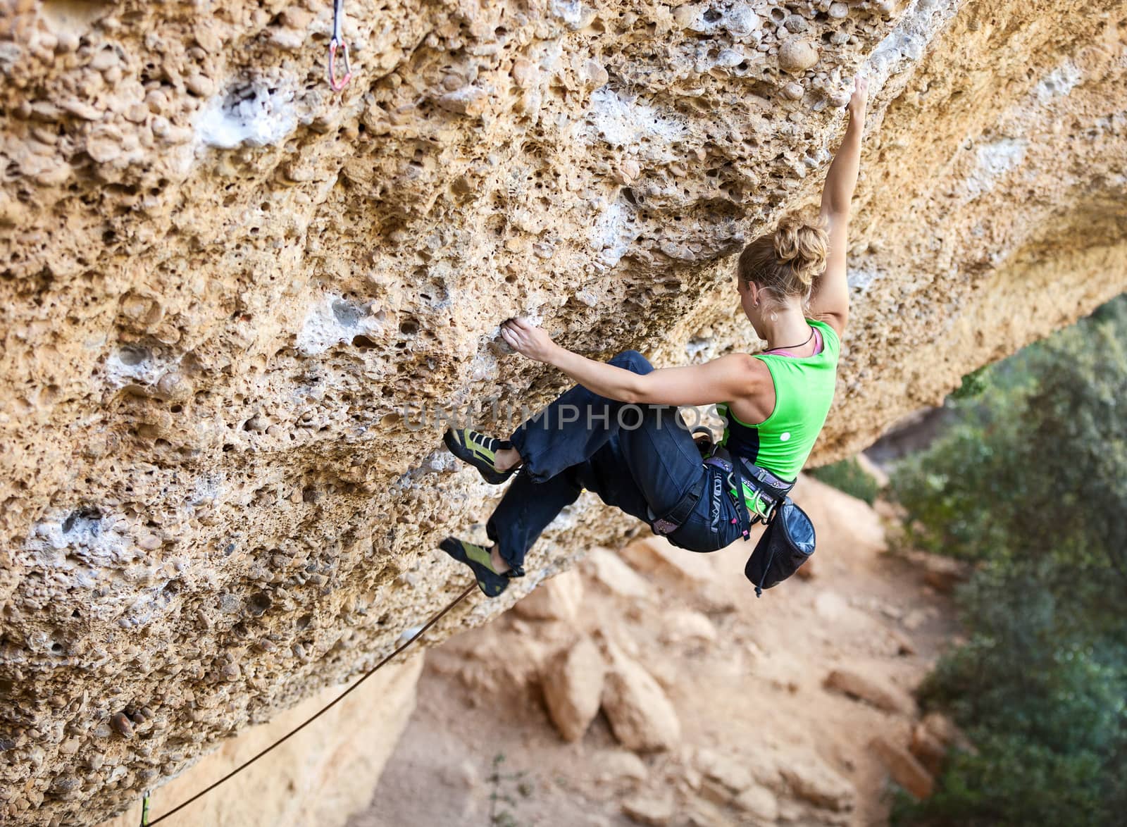 Young female rock climber on a face of a cliff