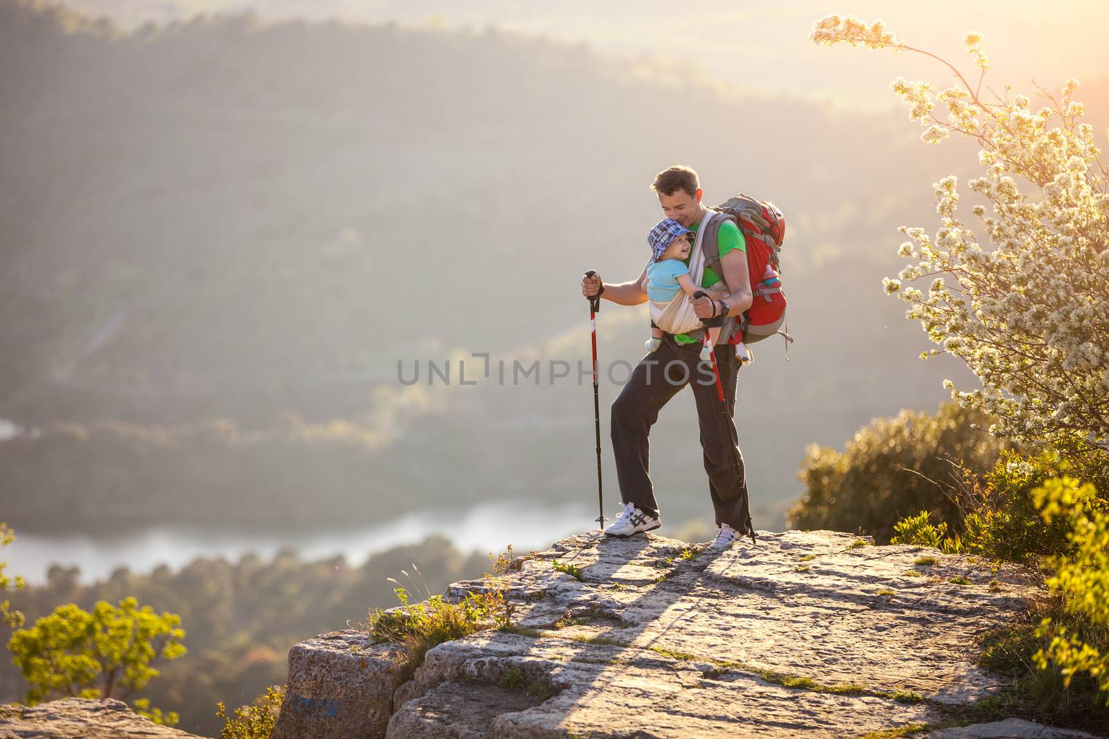 Hiker with baby relaxing on cliff by photobac