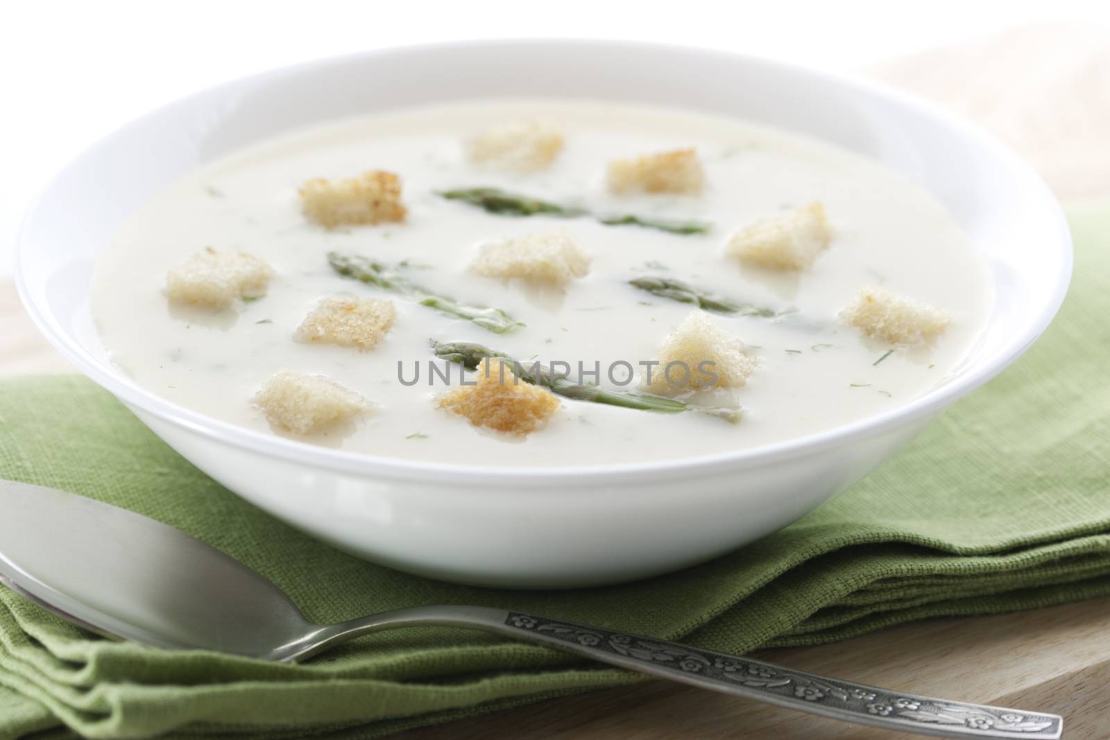 Bowl of asparagus soup with croutons on white background 