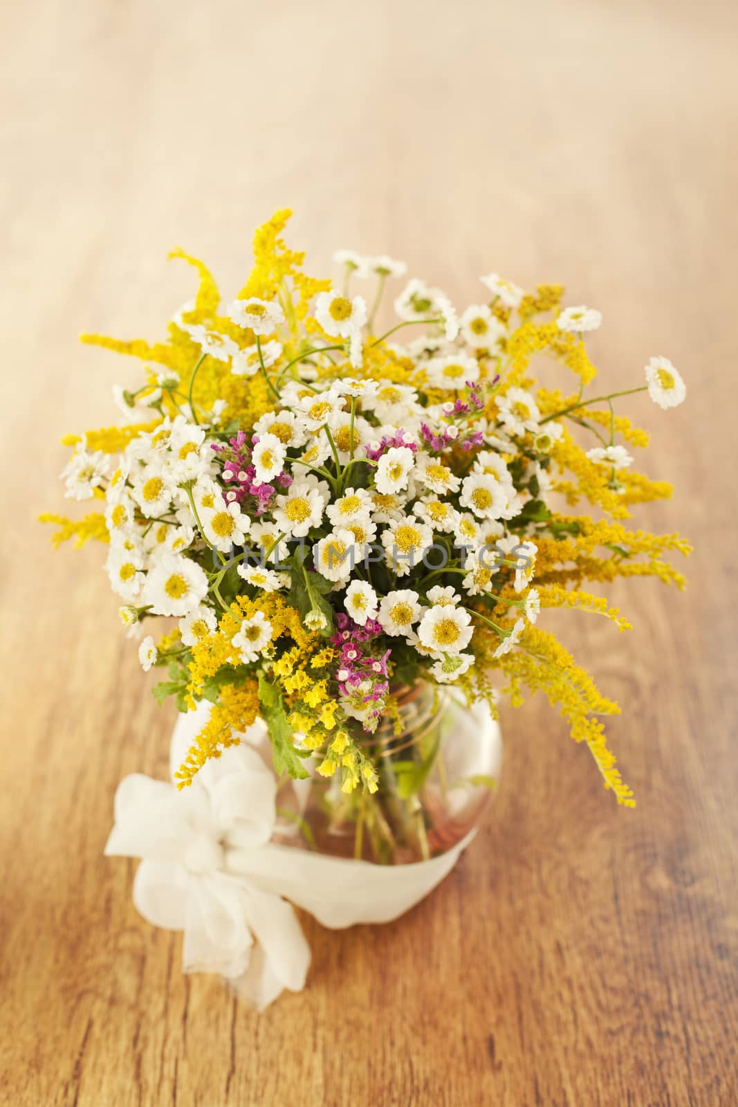 Beautiful bouquet of wildflowers in vase on wooden background