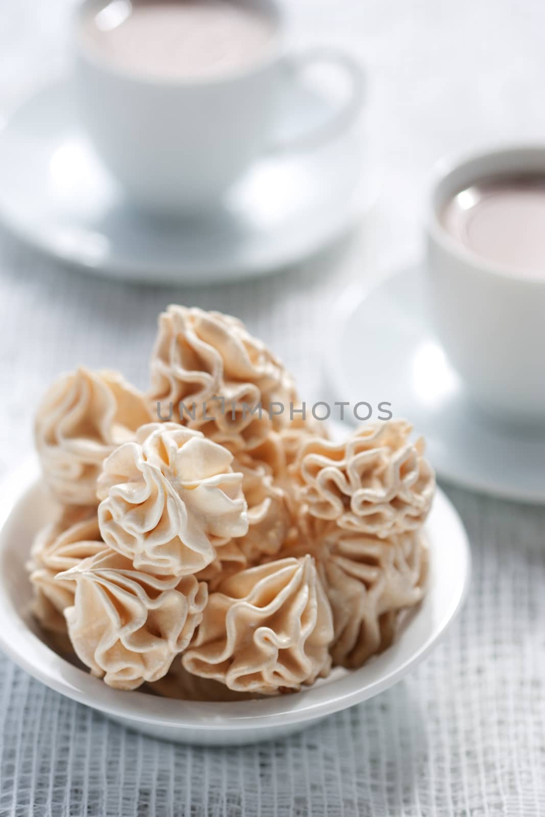 Meringues and two cups of chocolate drink, shallow dof.