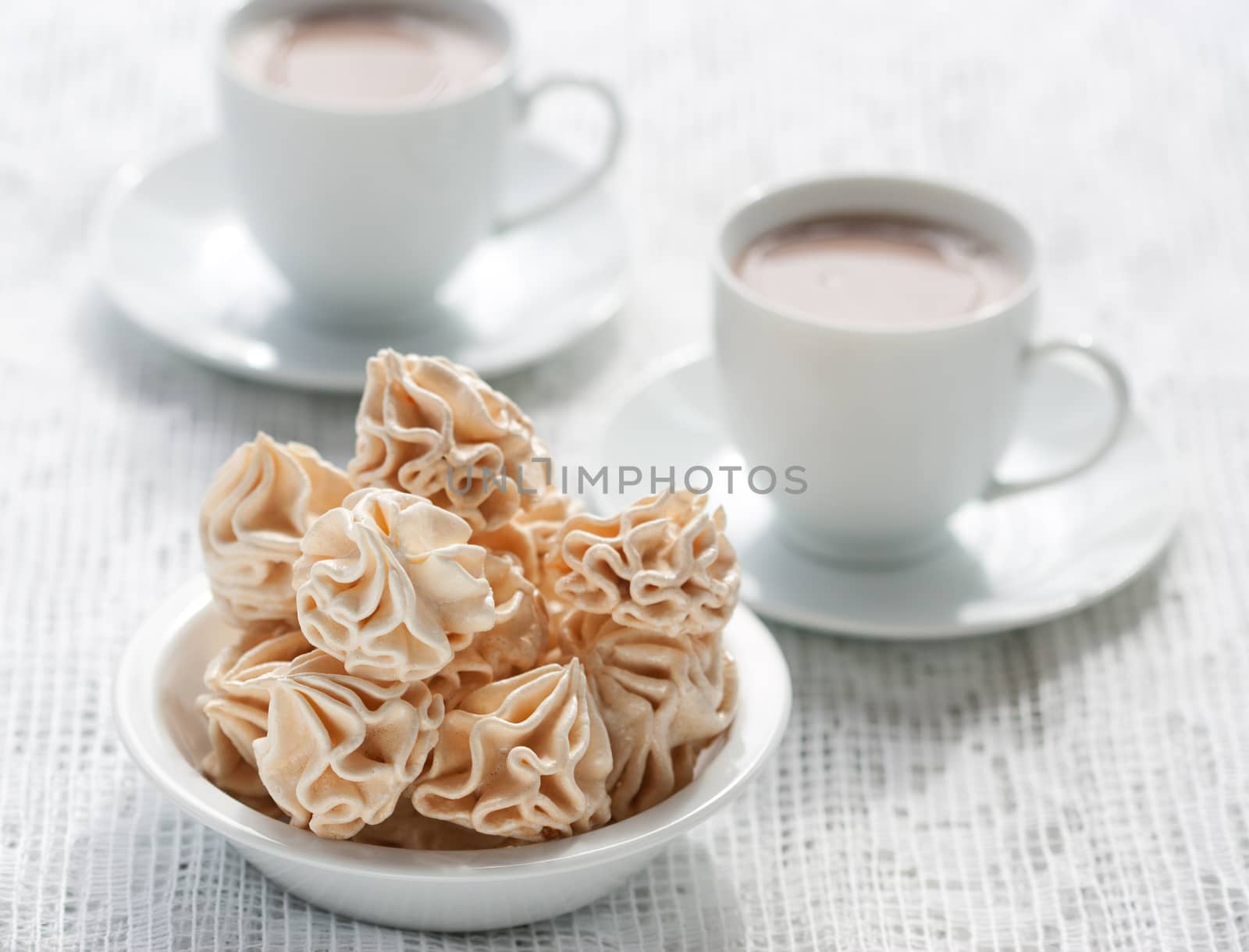Meringues and two cups of chocolate drink, shallow dof.