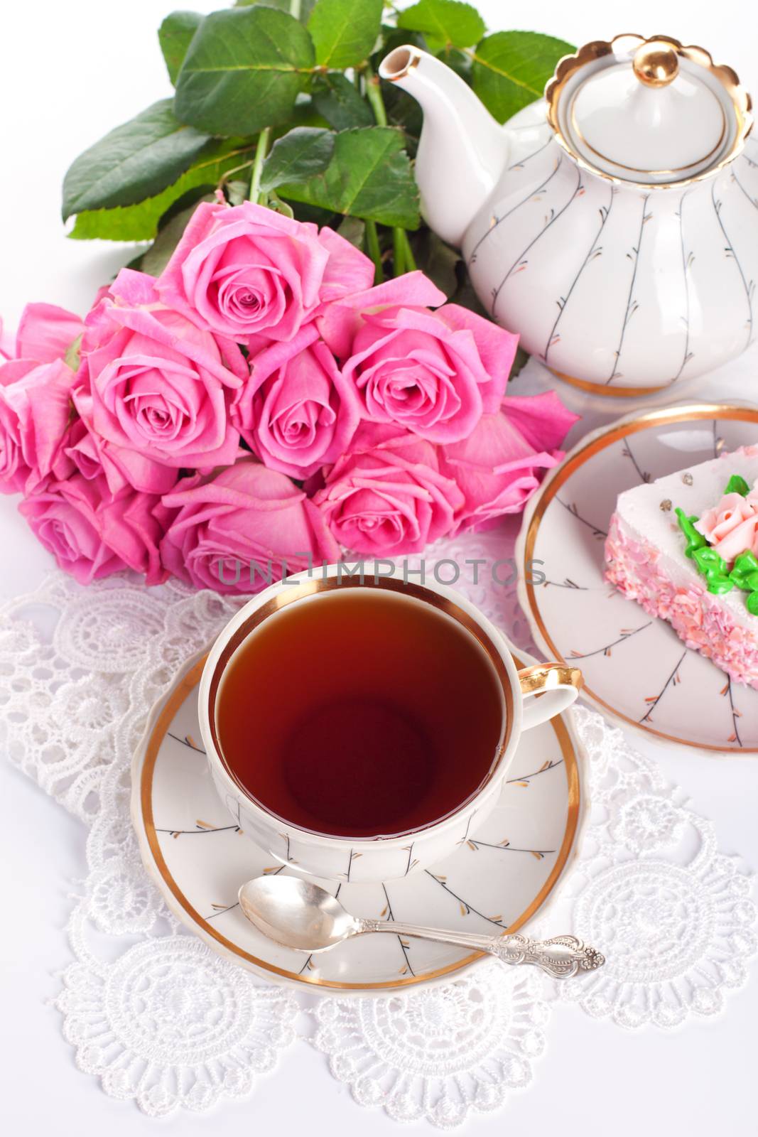 Closeup of cup of tea with cake and roses 
