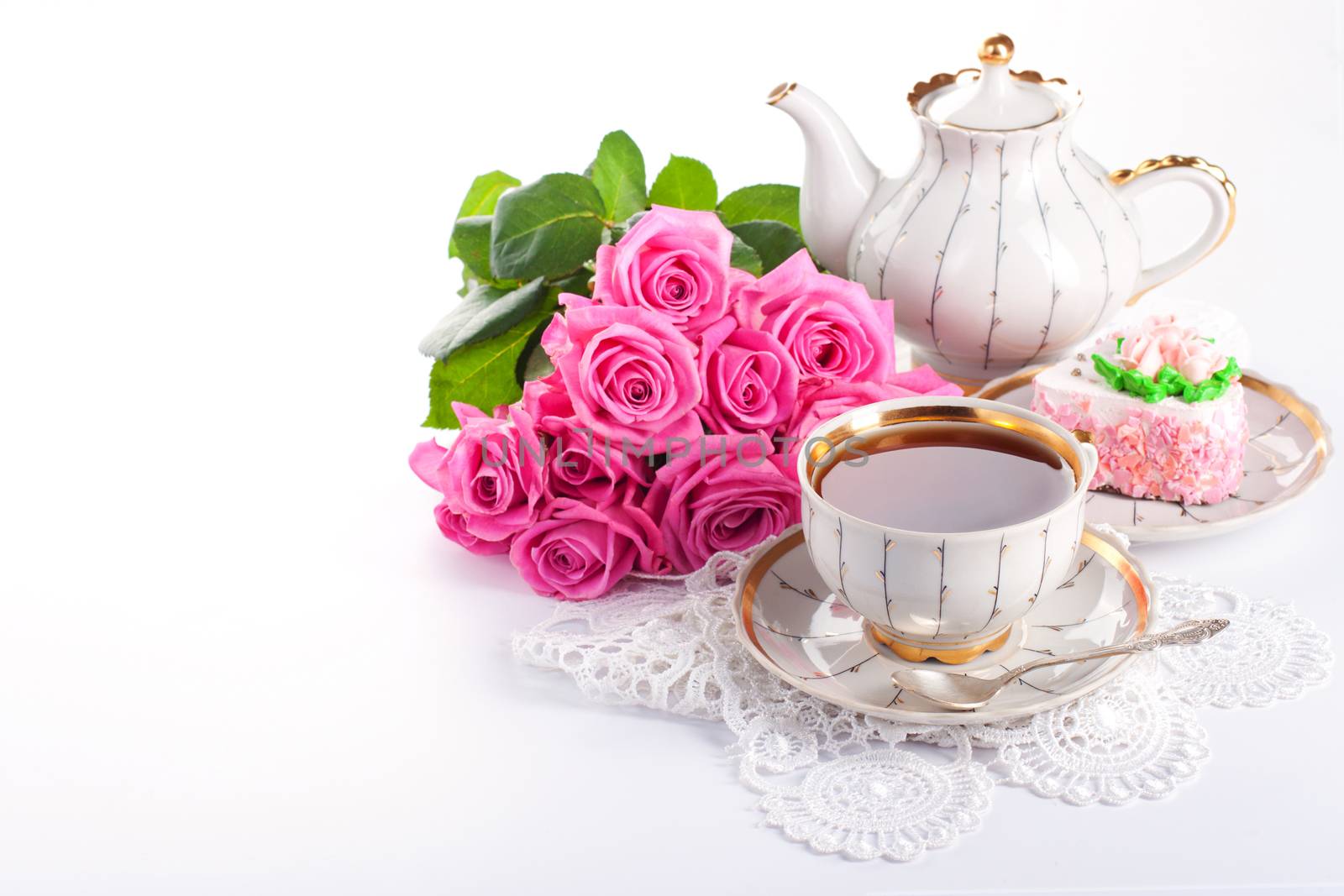Closeup of cup of tea with cake and roses 