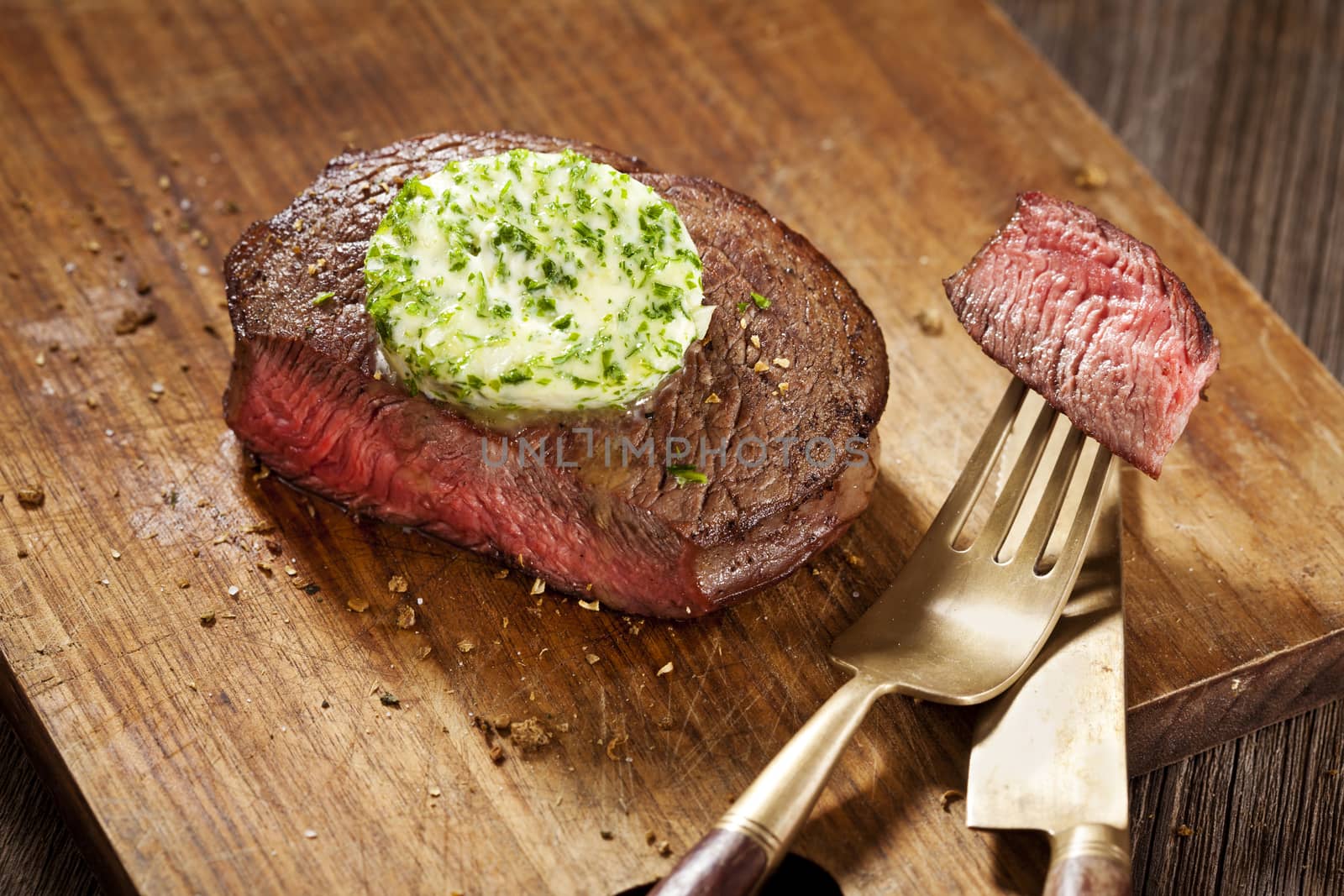 Steak with green butter on wooden board