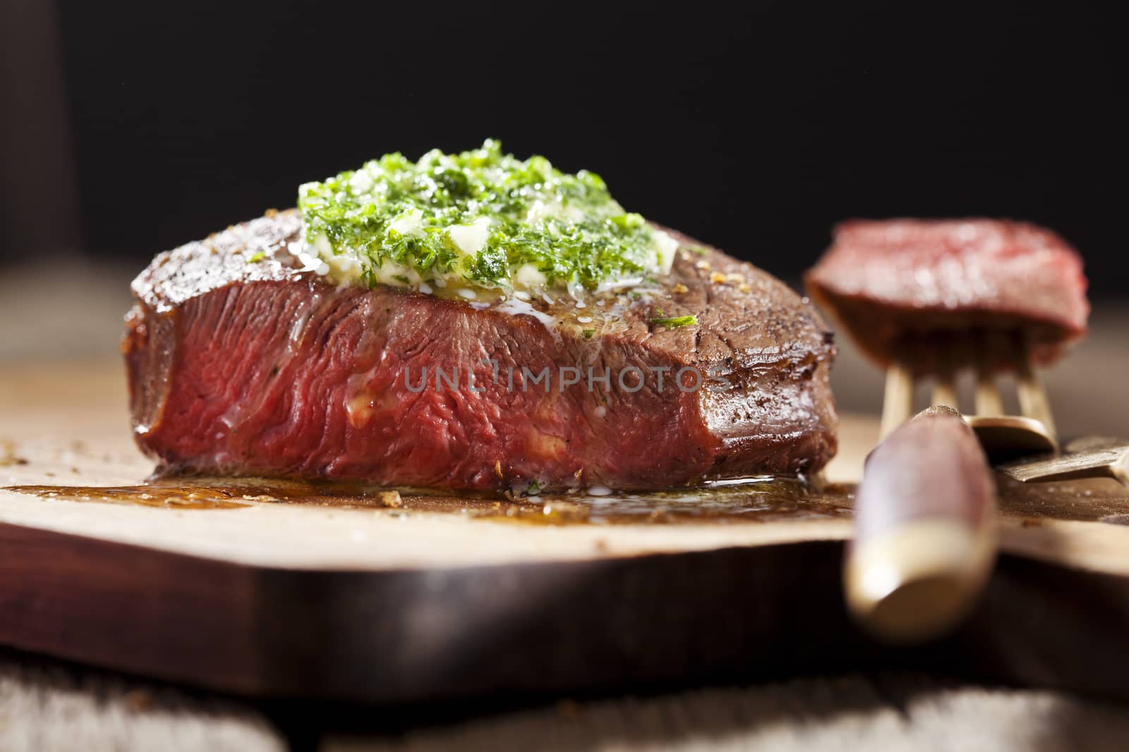 Steak with green butter on wooden board
